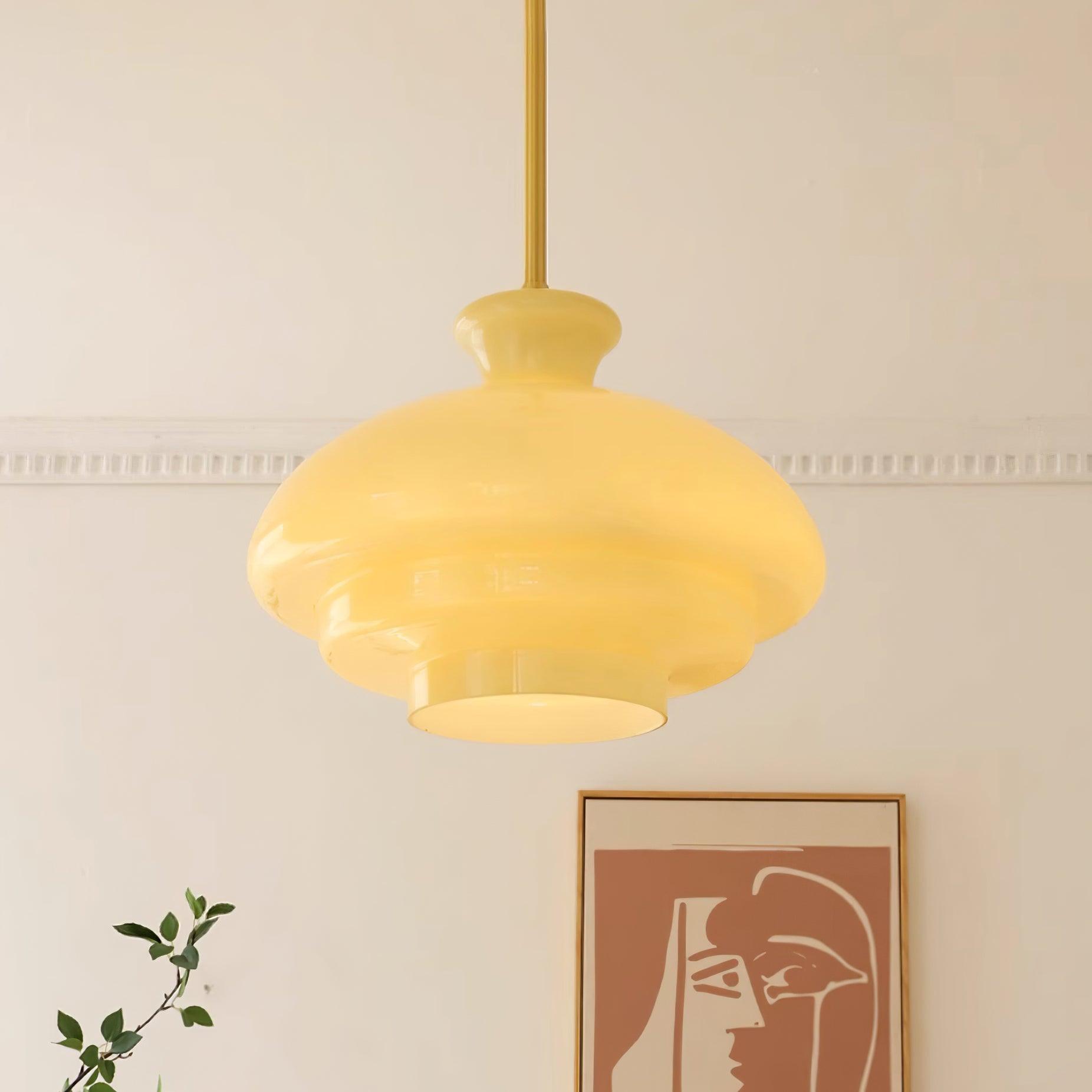 Glowing yellow dome pendant in front of orange two-face artwork and a green branch