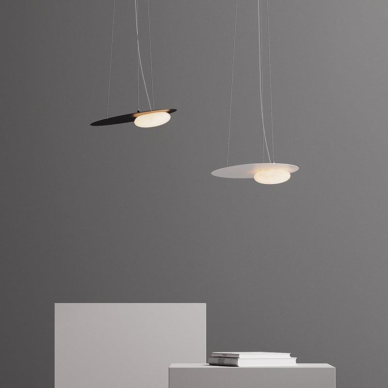 Black and white disc pendants at different heights against grey, above white blocks and stacked books.