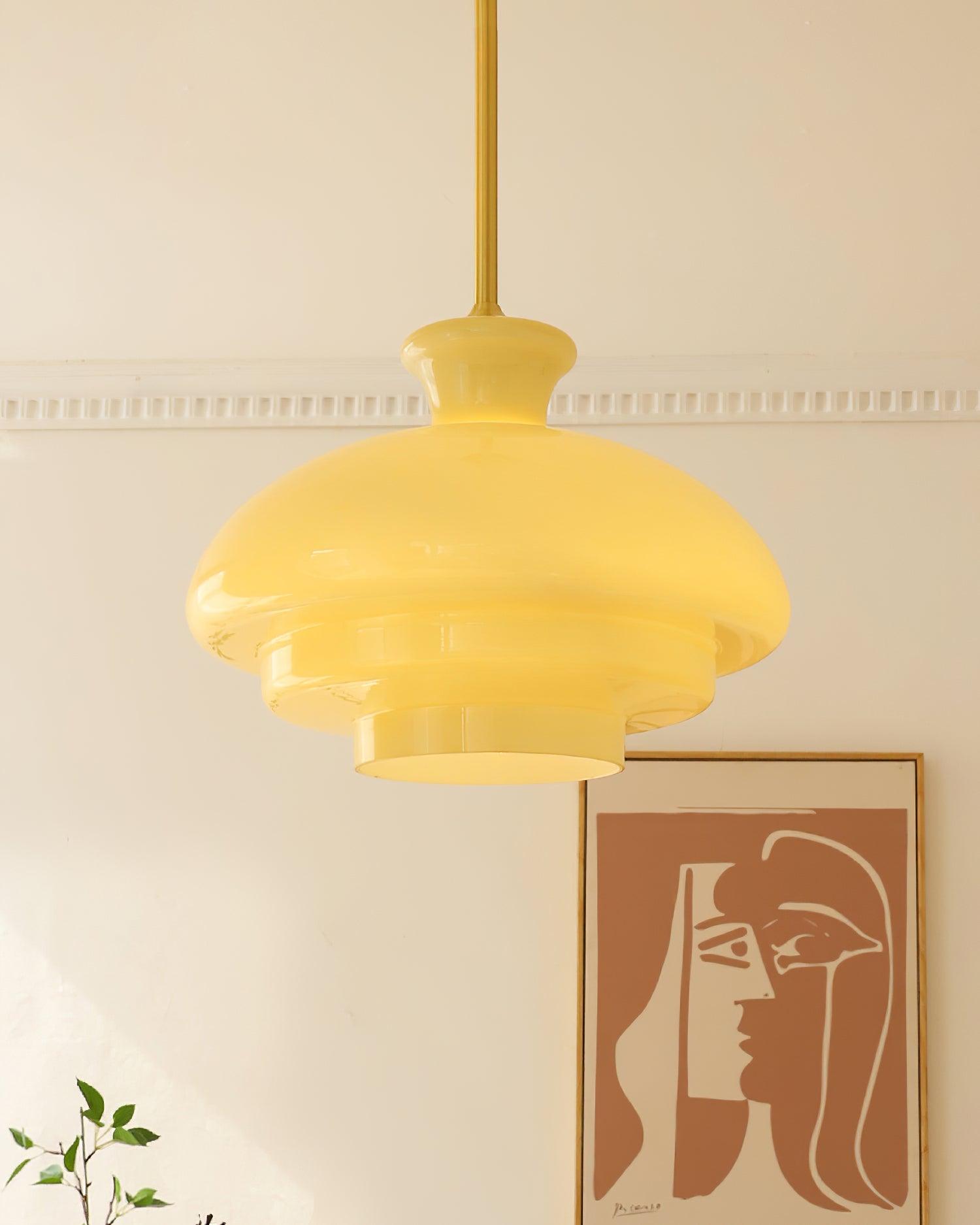 Close room view of a glowing yellow stepped dome and gold-tone rod with orange artwork behind