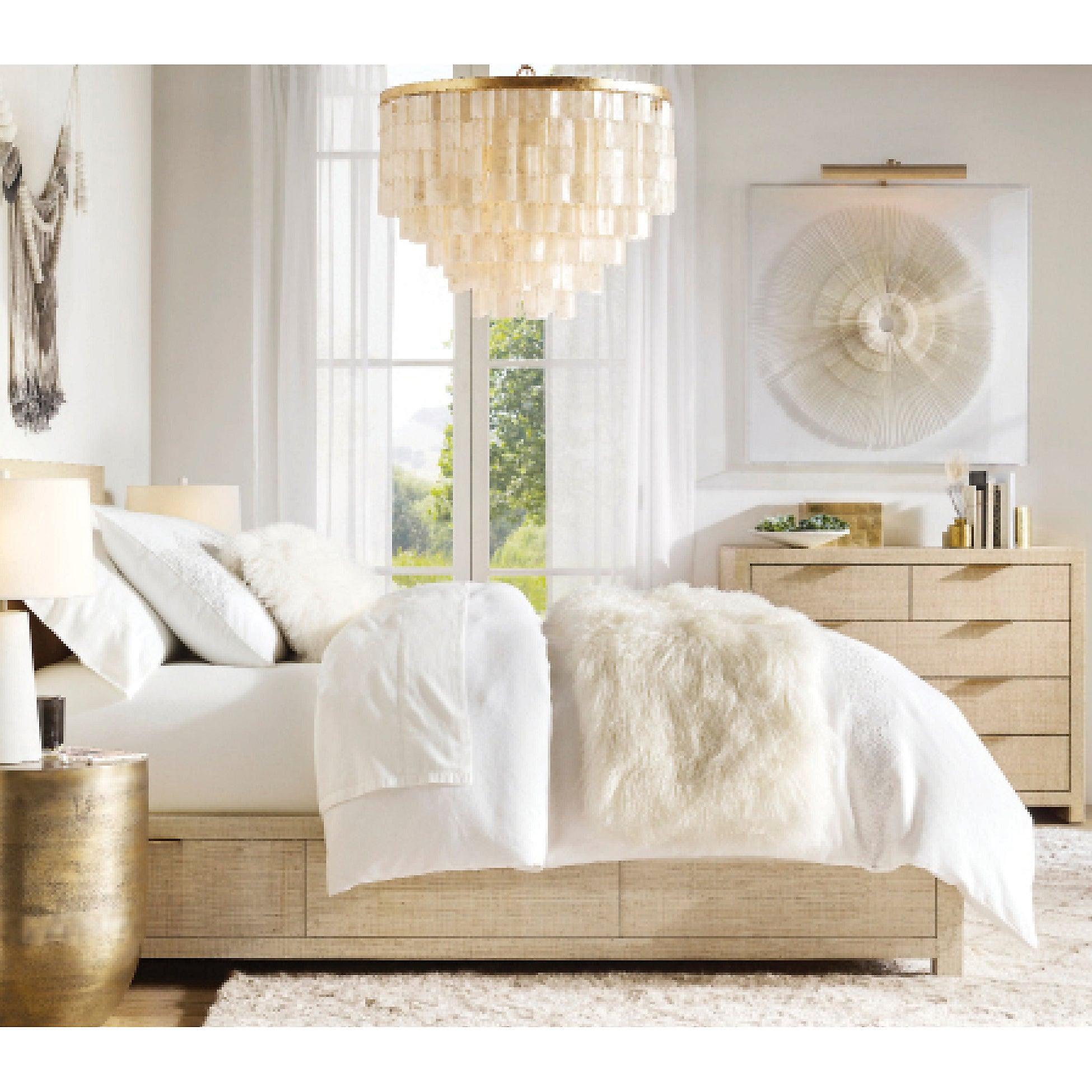 Shell pendant over a white bed near pale wood drawers, curtains and fan-pattern wall art