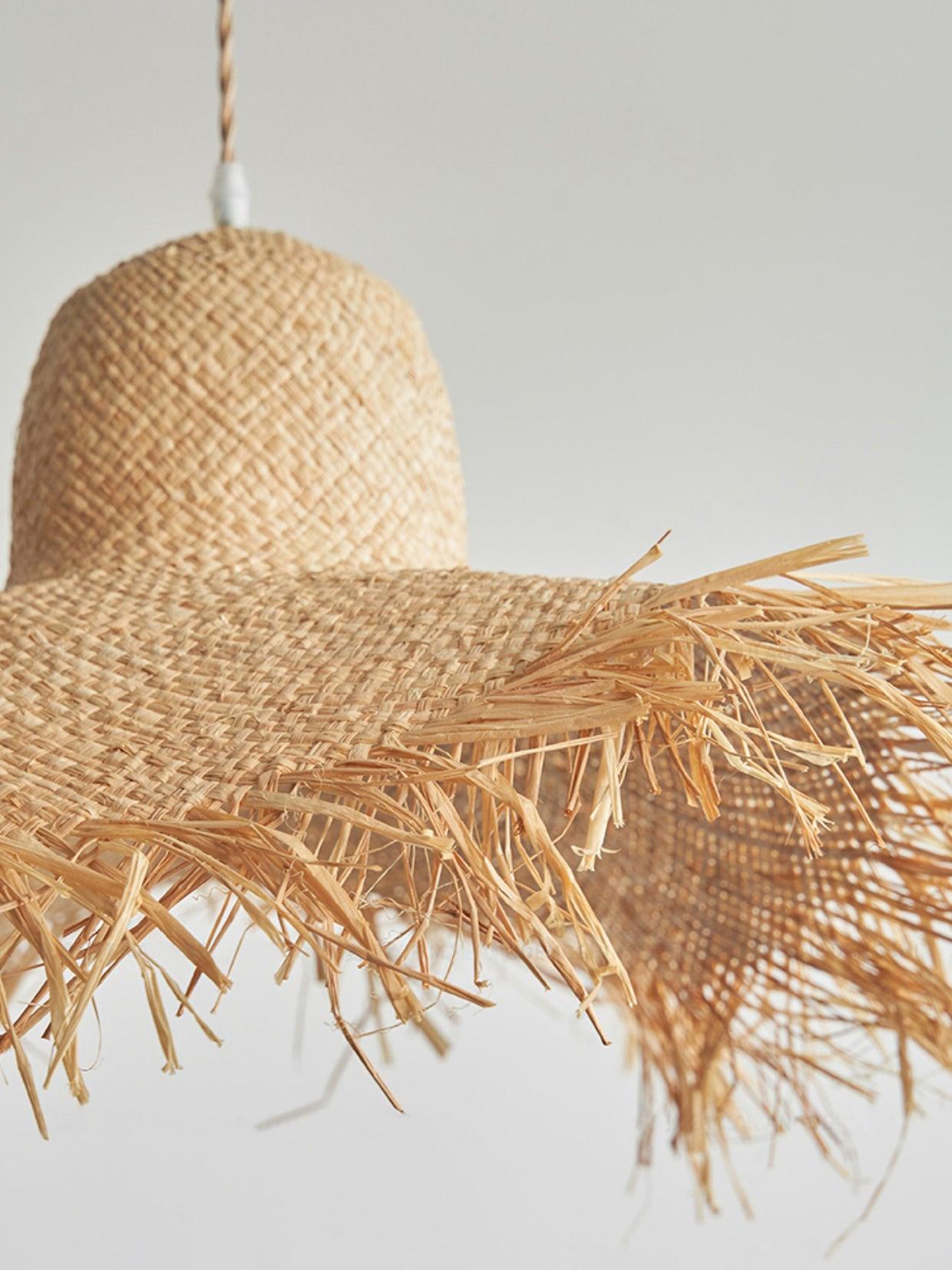 Unlit close-up of crosswoven crown, folded brim and loose fringe fibers on the rattan hat shade