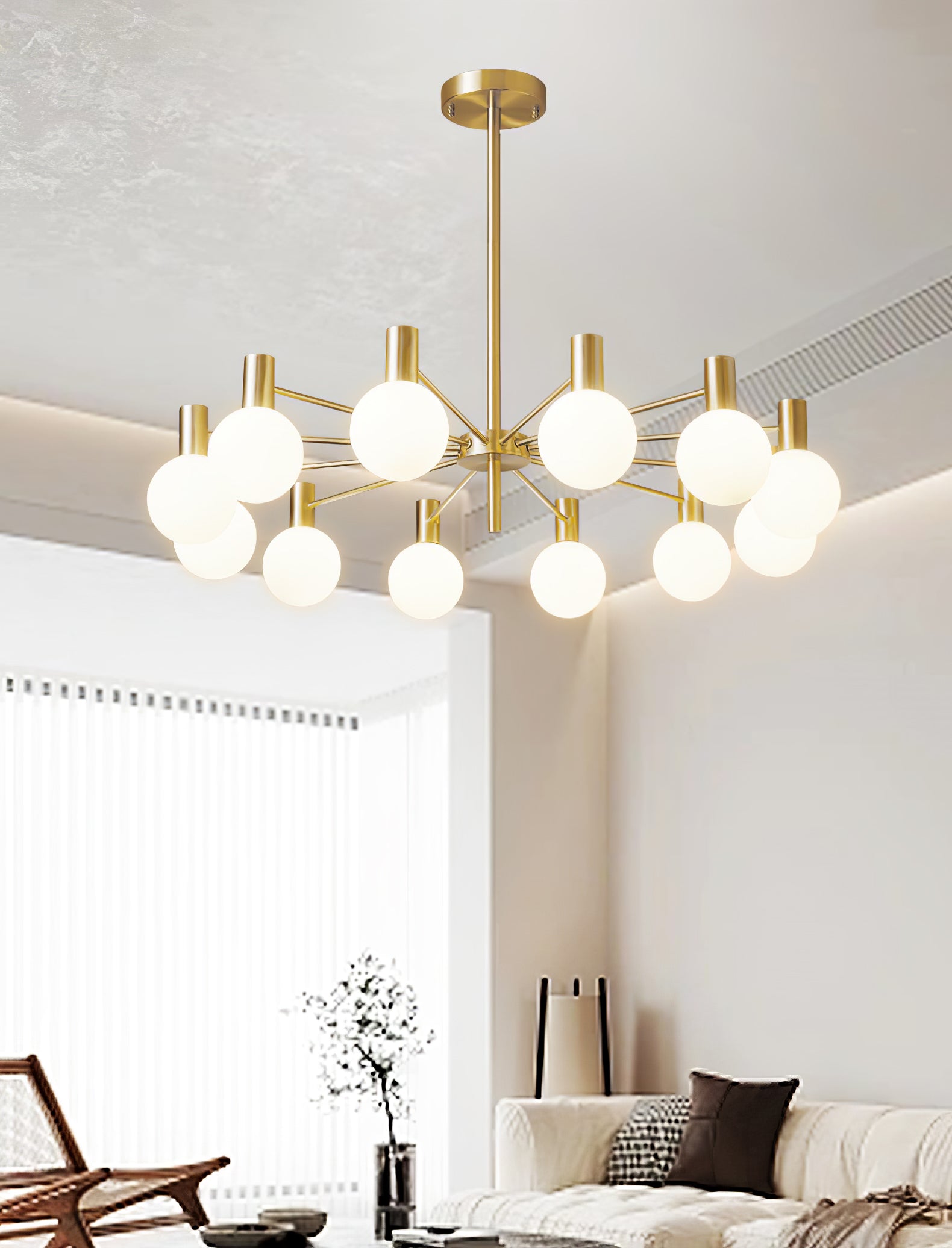 Twelve-white-globe chandelier above a white textured sofa and wicker chair, with a black vase and tall floor lamp.