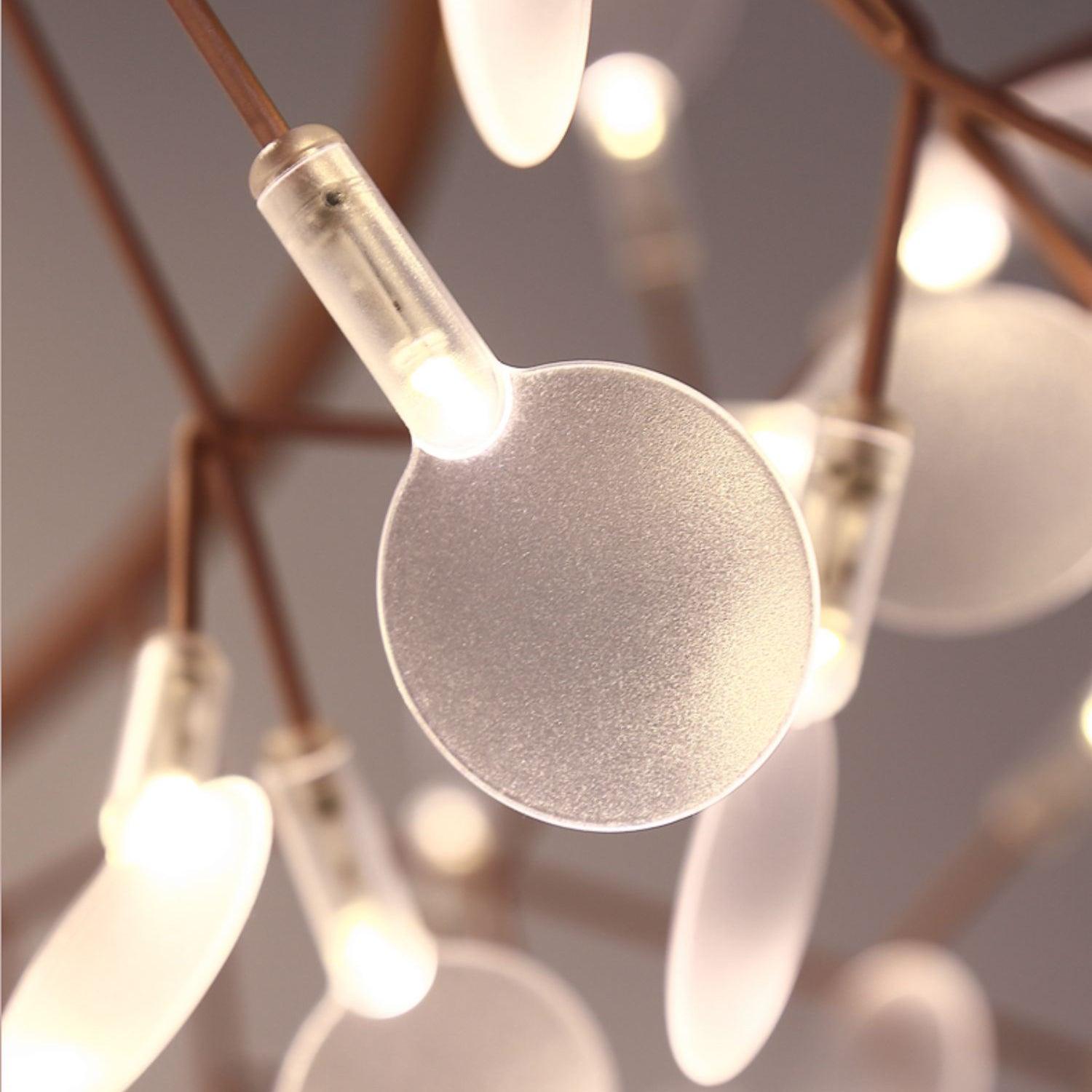 Close-up of a frosted round leaf disk and glowing LED sleeve on a rose-copper branch