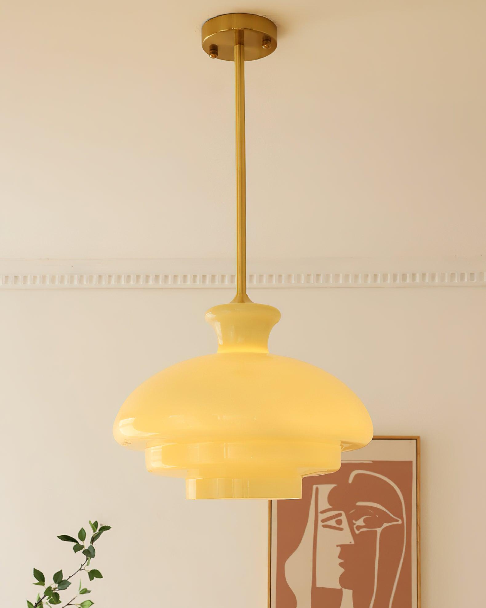 Alternate glowing yellow dome with gold-tone rod and canopy beside framed artwork and a branch