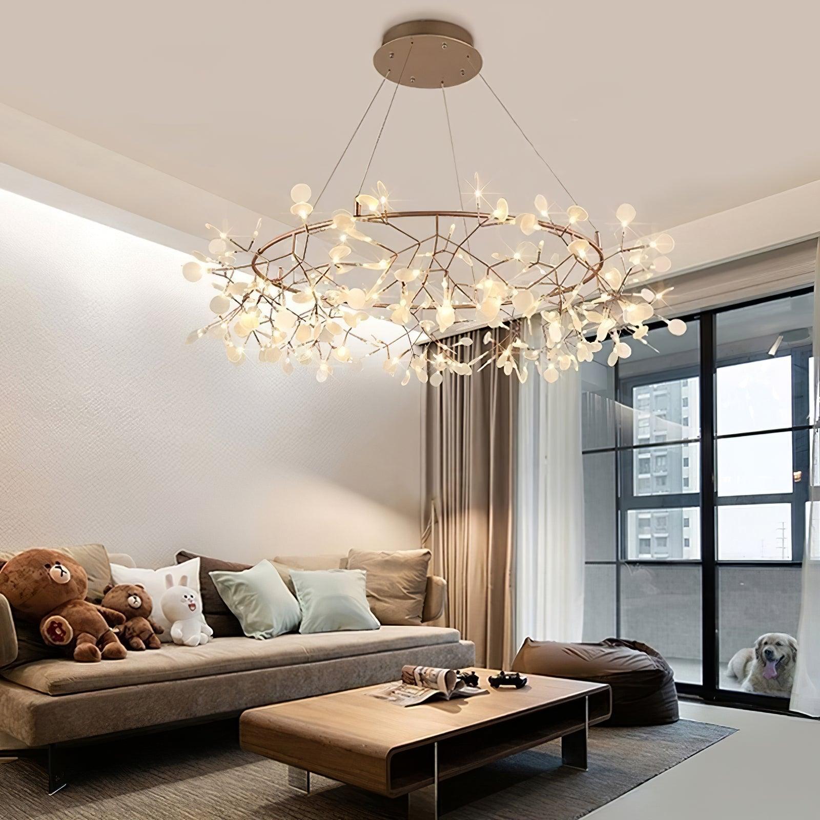 Warm metallic leaf ring chandelier above a pale sofa with bear and rabbit cushions beside black balcony doors