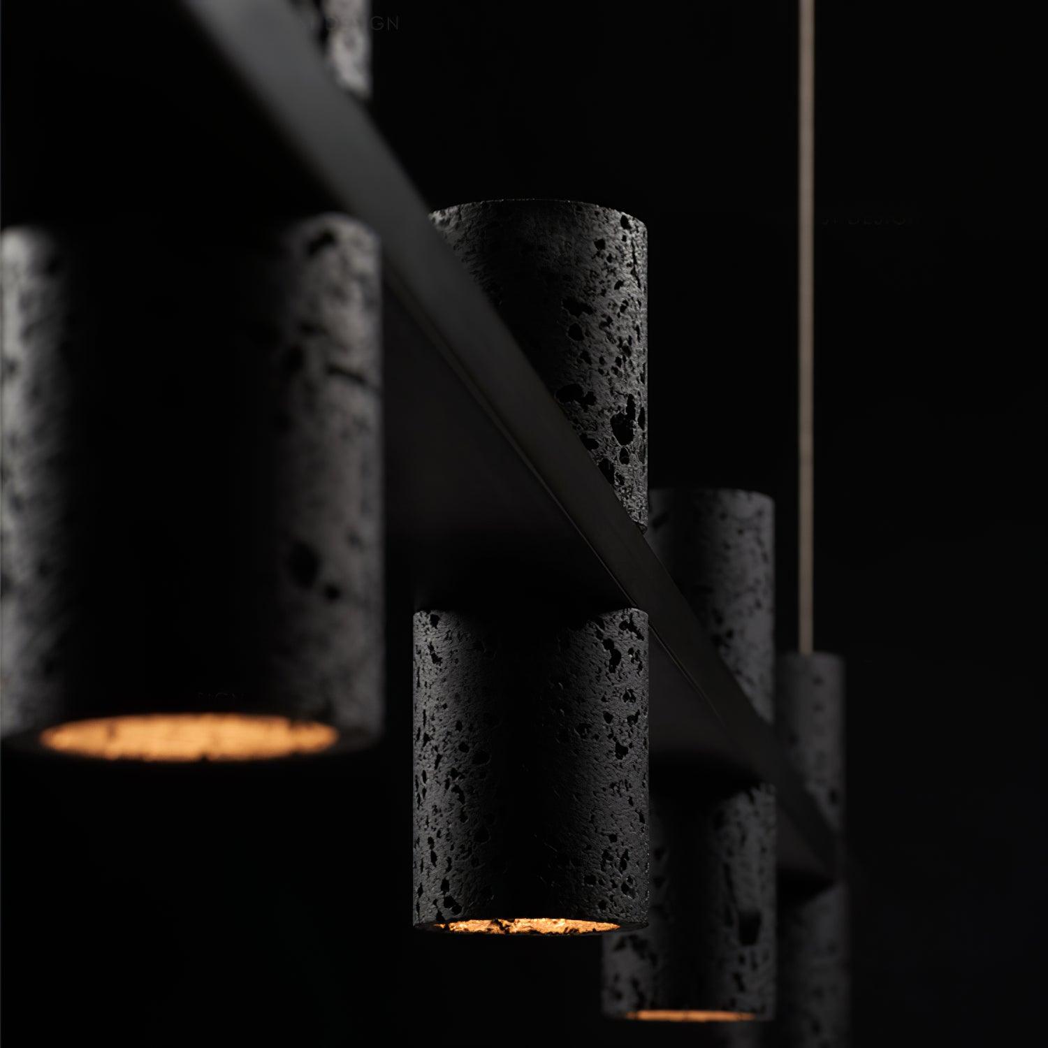 Dark close perspective of pitted black stone cylinders along diagonal bar, with orange-yellow light at lower openings.
