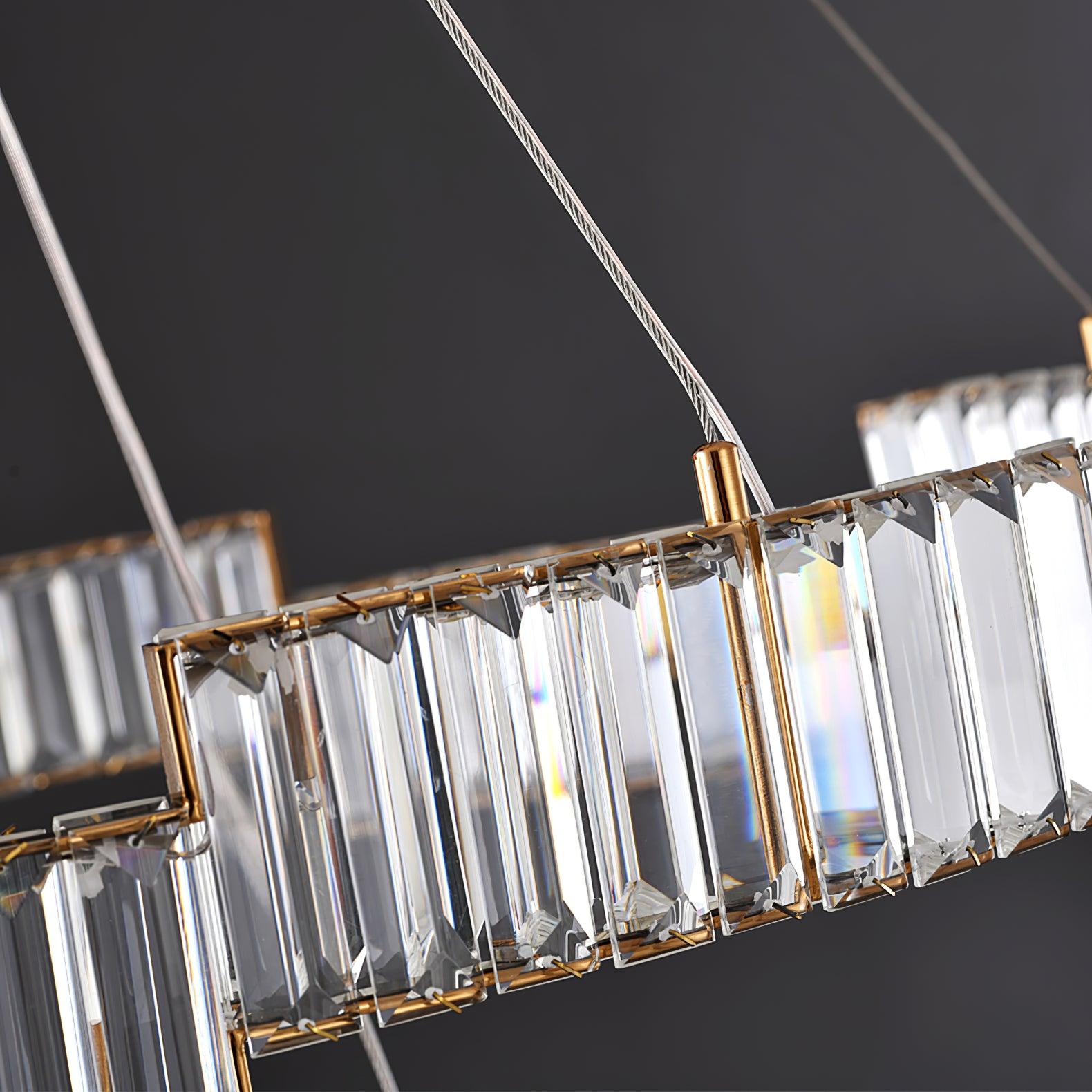 Close unlit faceted glass panels, retaining clips, gold-tone rail, cable connector and twisted wire on a dark background