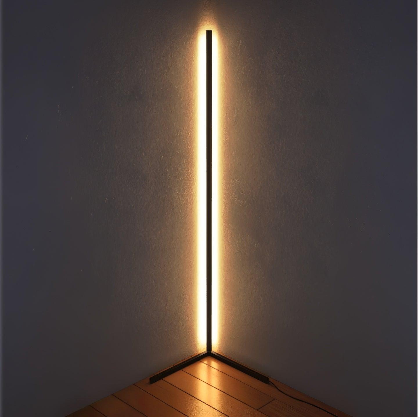 Black floor lamp casting warm light into a bare corner above a wooden floor