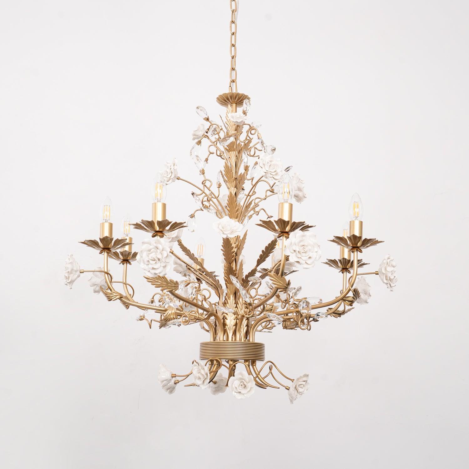Low upward view of unlit eight-light chandelier, showing gold-tone candle arms and white ceramic roses below the ribbed hub