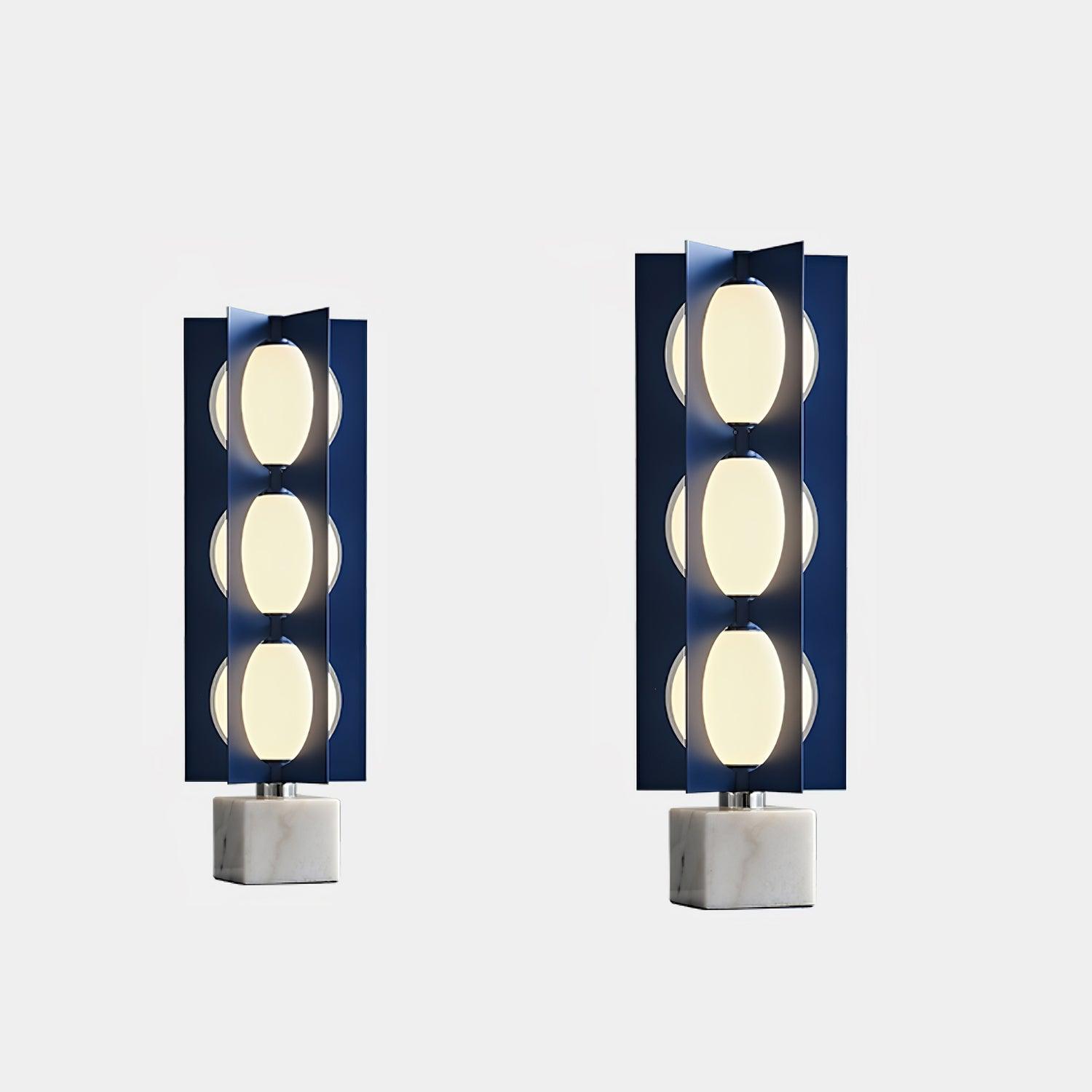 Two illuminated three-level blue column lamps pictured side by side with white marble bases