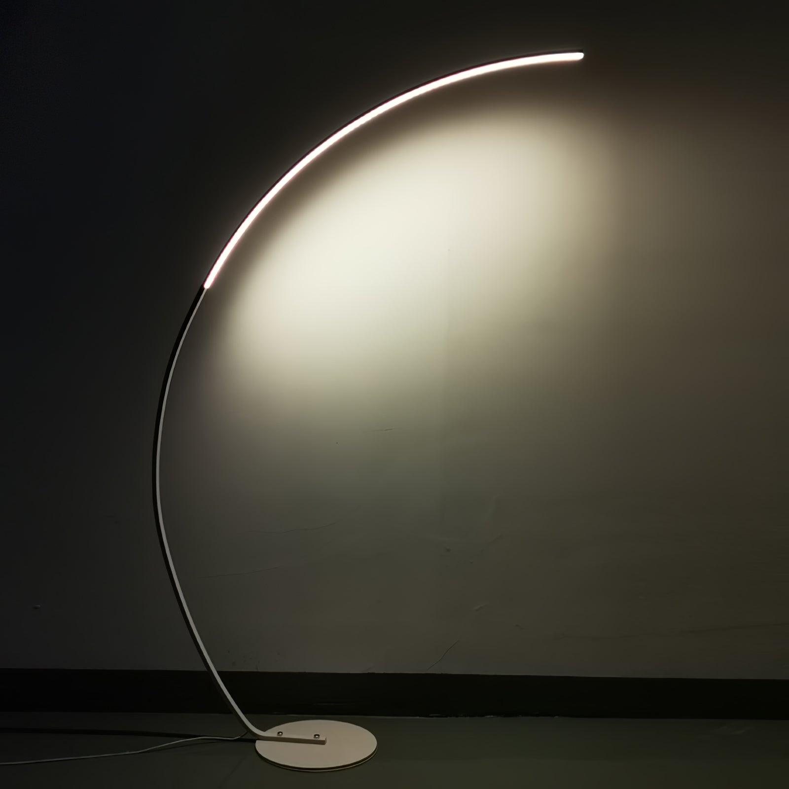 White Arc floor lamp glowing against dark plain wall, with continuous upper light strip and low white base