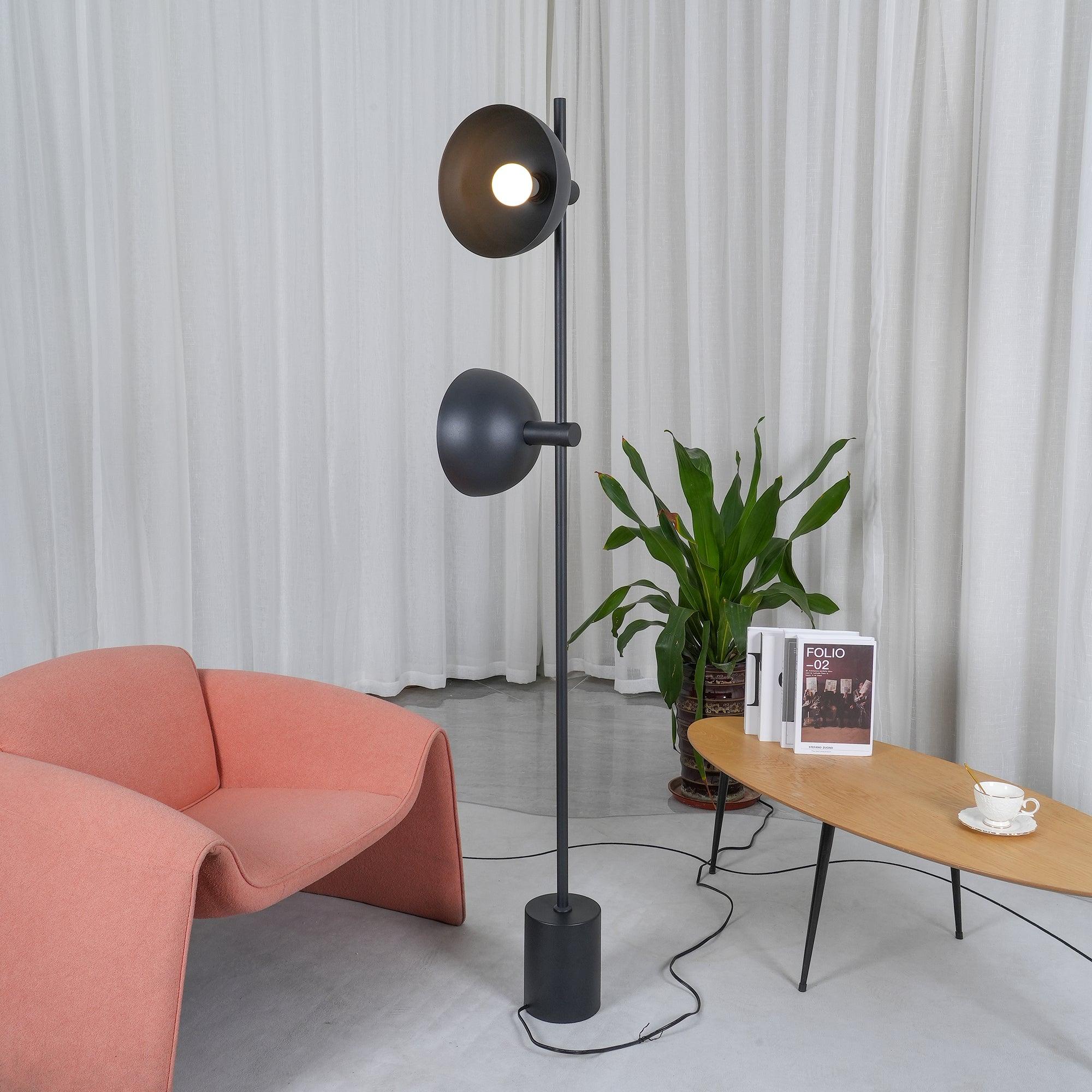Studio floor lamp beside a coral chair, with the upper head lit and lower head facing away.