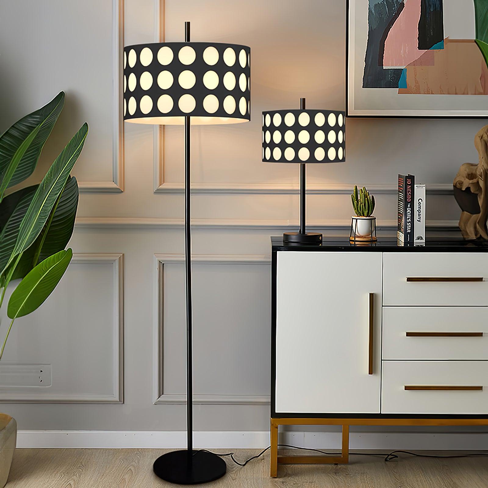 Straight black floor lamp and smaller matching dotted-shade table lamp beside cabinet, plants and abstract artwork