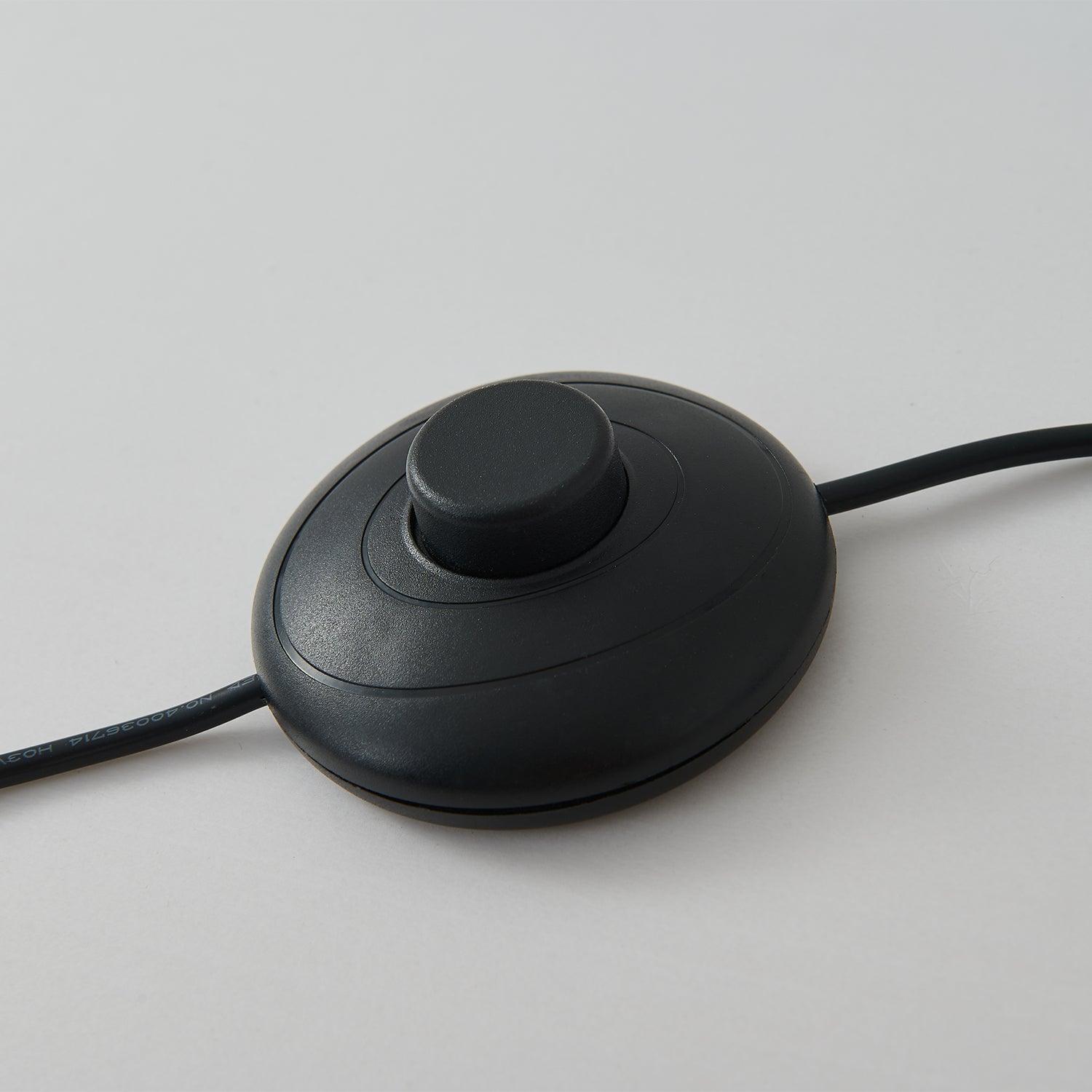 Close-up of a round black cord-mounted push-button switch with cable on both sides
