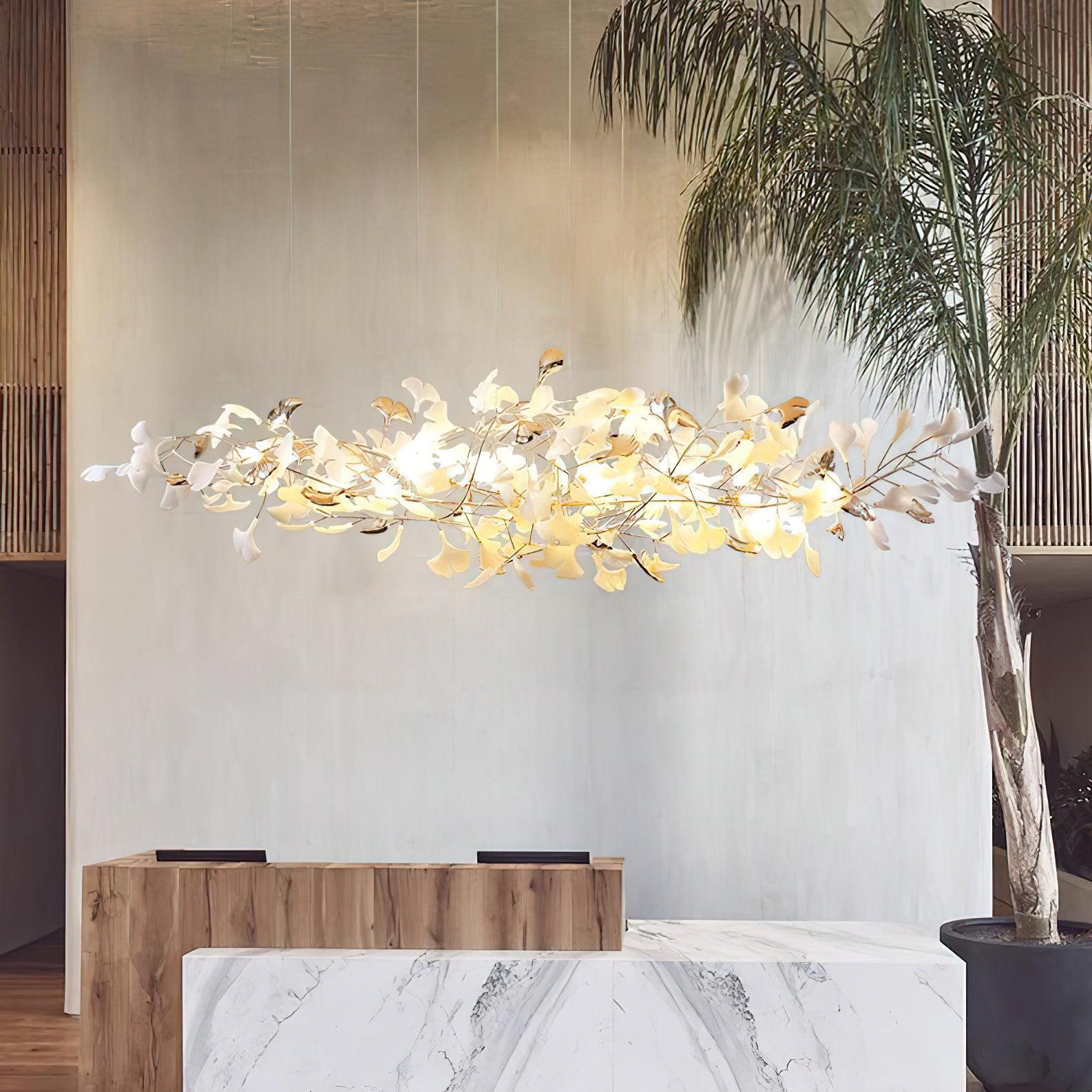Horizontal white-and-gold leaf cloud above wood-and-marble counters beside a tall potted palm