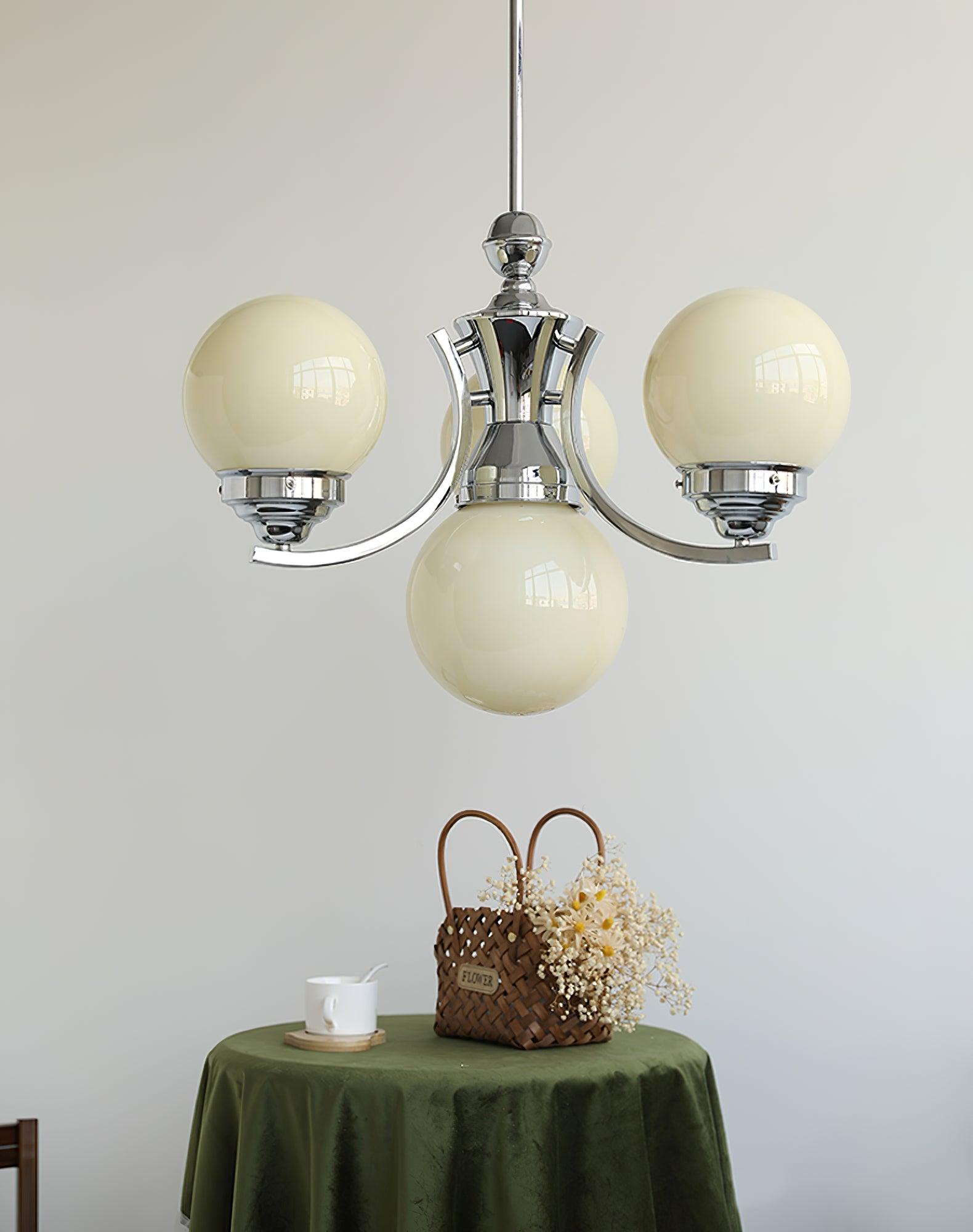 Pale beige-looking glass globes on compact rising chrome arms above a green table and flower basket