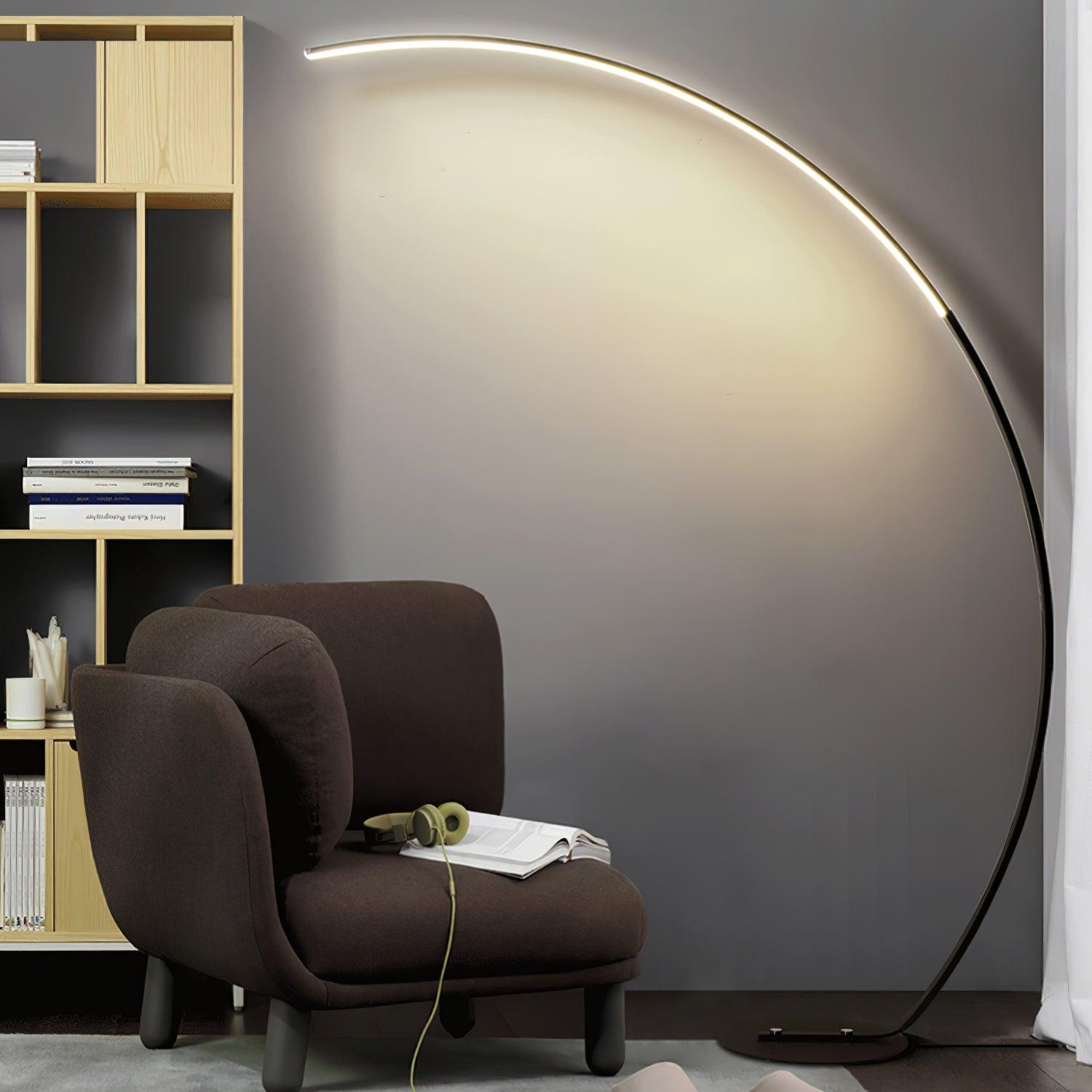 Black Arc floor lamp beside brown chair with open book and headphones, wooden cubby bookcase and curtain
