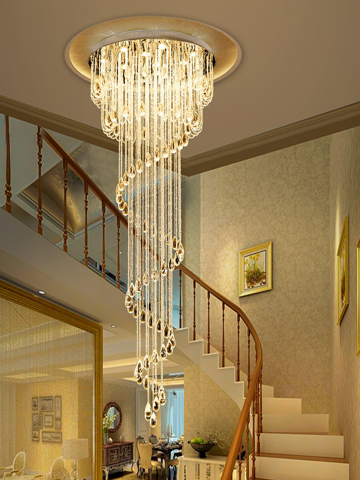 Long warm-lit crystal spiral before a curved wood stair rail and pale steps, with a large mirror at left