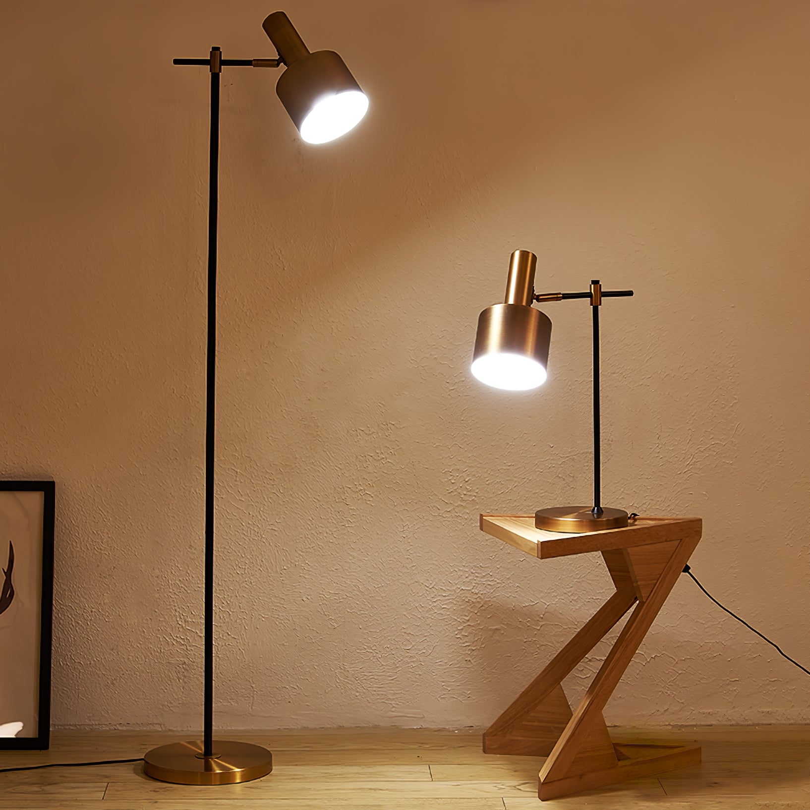 Lit black and gold floor lamp beside matching table lamp on zigzag wooden table against a textured warm wall