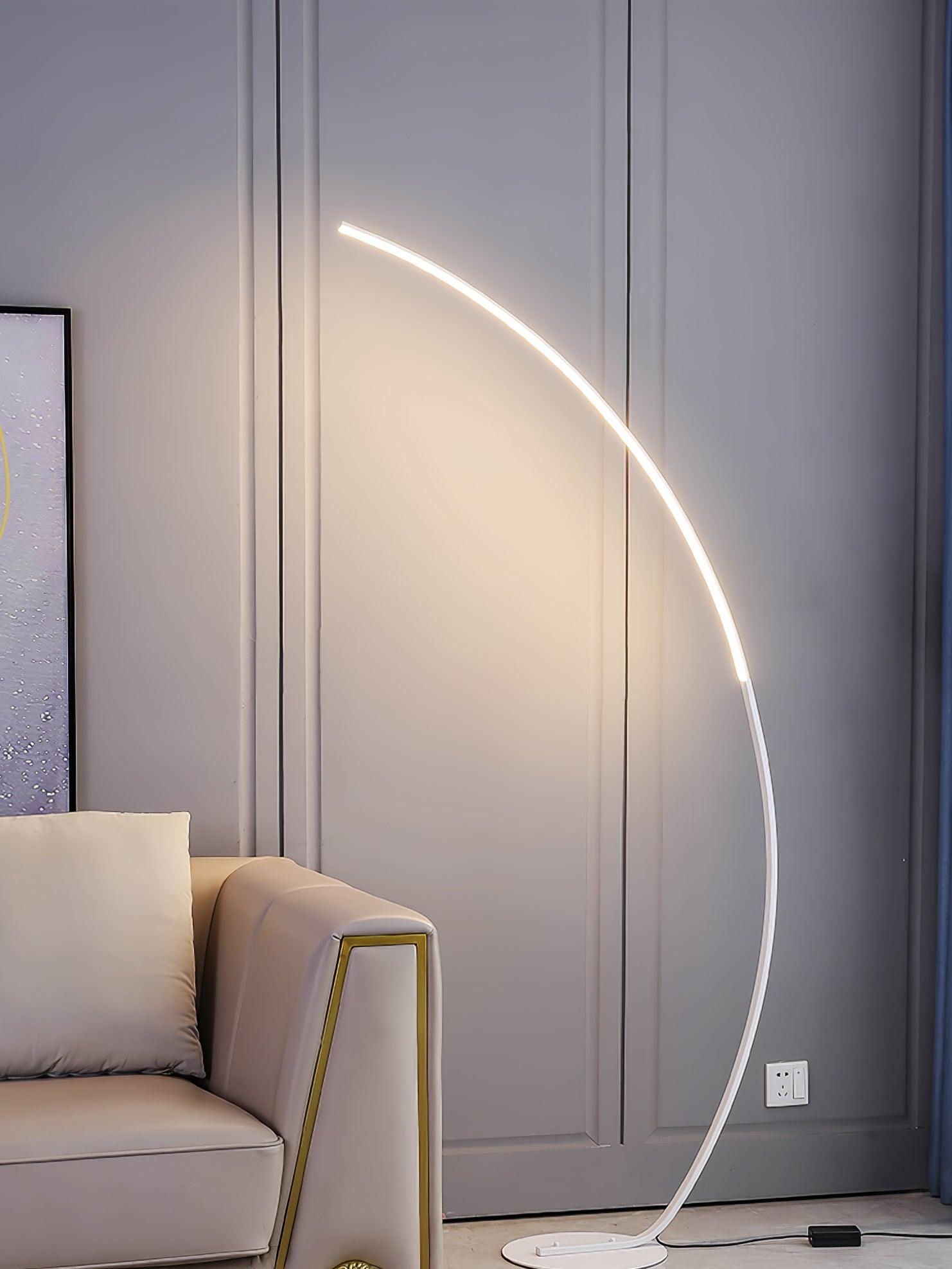 White Arc floor lamp beside cream sofa and pale moulded wall, showing low base, black cable and rectangular box