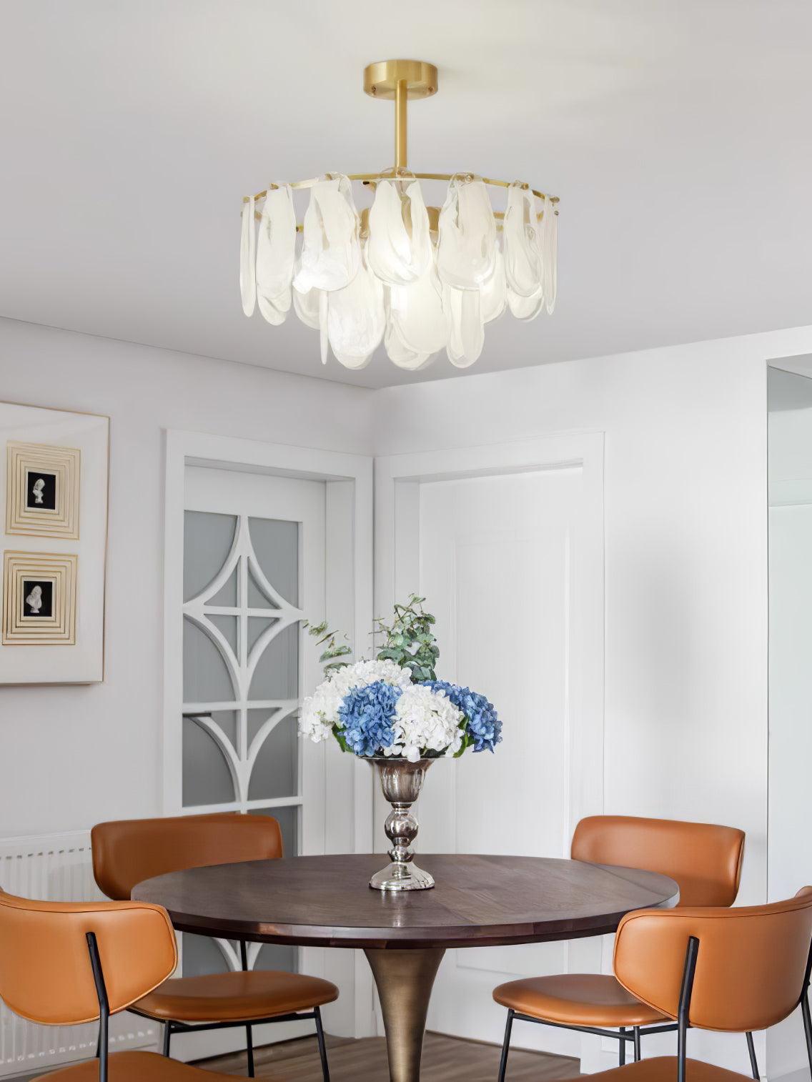 Round Cloud glass pendant above a round wooden dining table with orange chairs and a blue vase