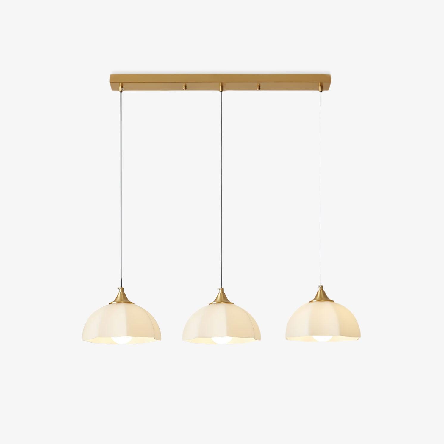 Three glass shades suspended from long brass ceiling bar