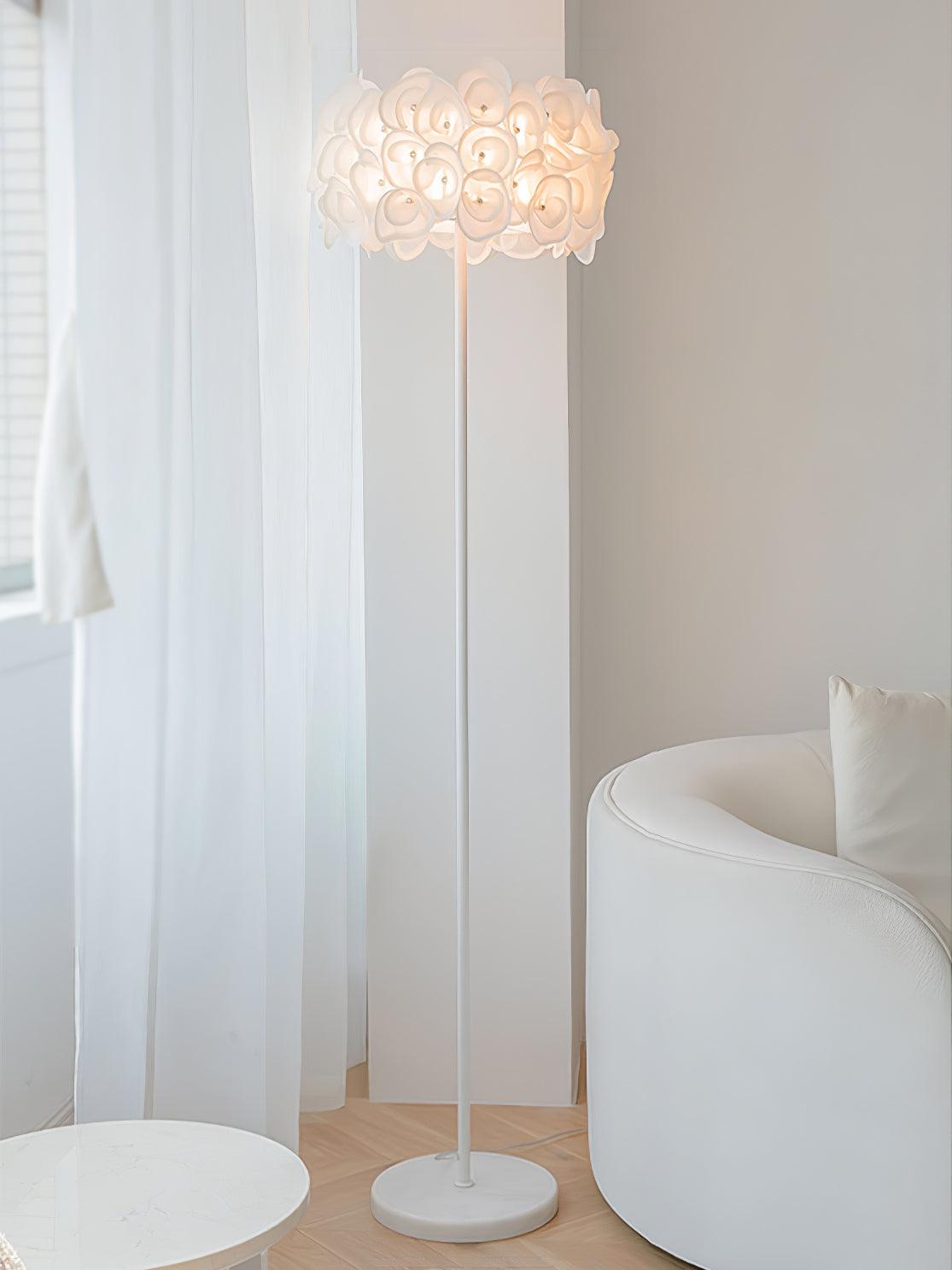 Wide upright petal lamp view by sheer curtain, white barrel chair and round white foreground table