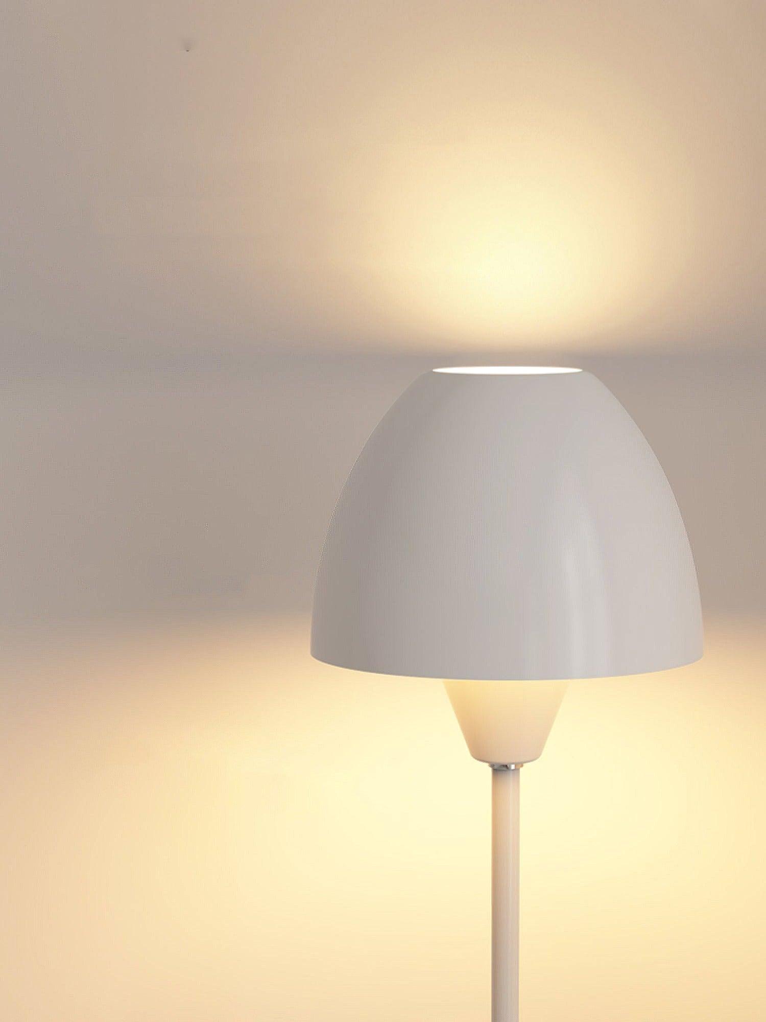 Close view of a white rounded shade with top and bottom openings above a small tapered cup and slim stem