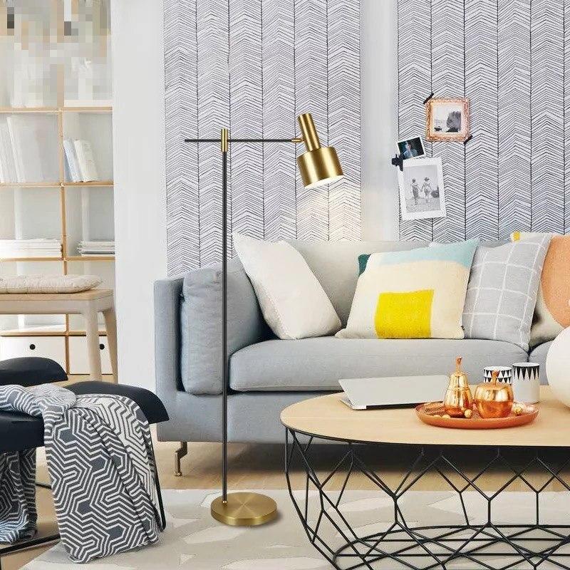 Lento floor lamp beside grey sofa, colourful cushions and round wood-topped coffee table with laptop and gold tray