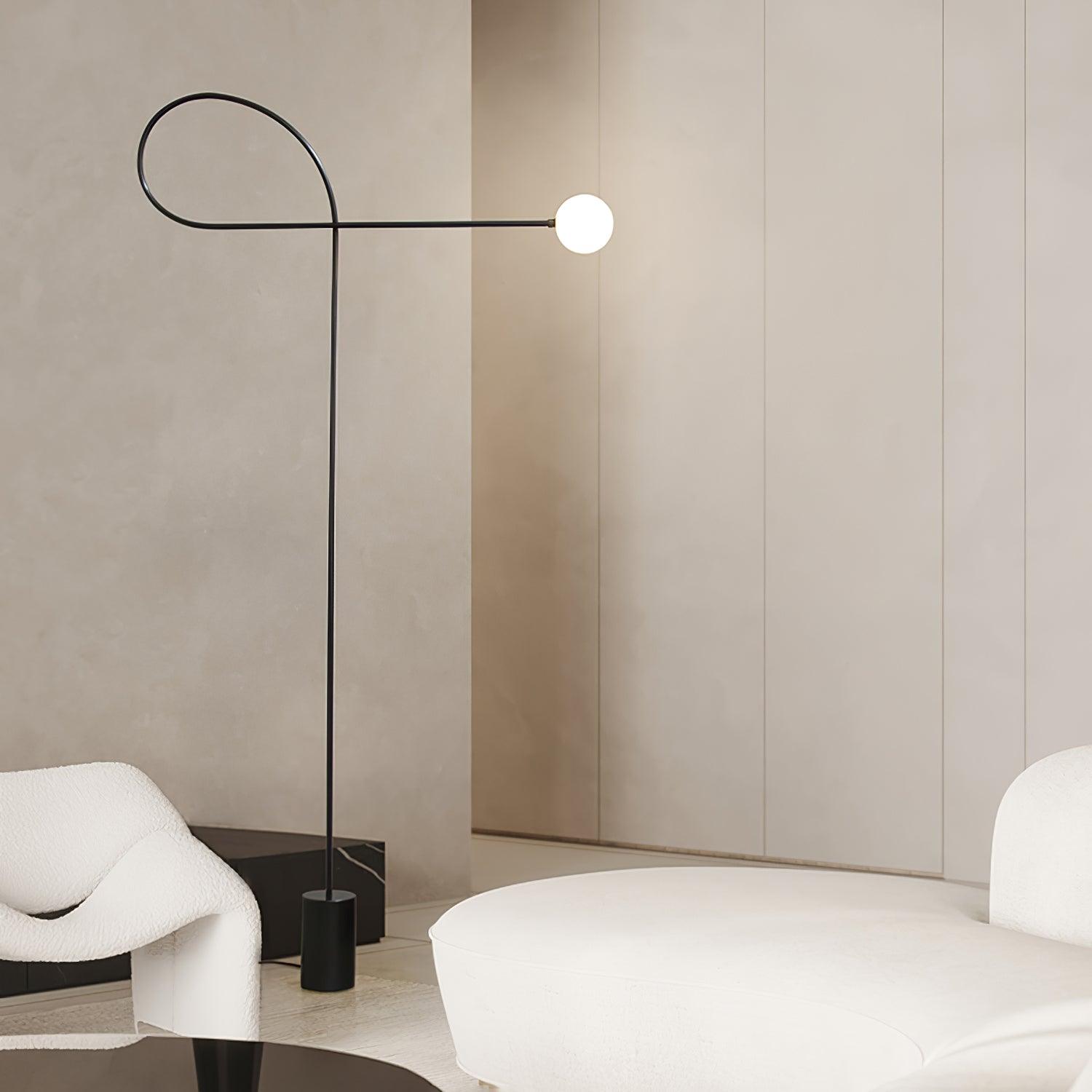 Lit Arcane Orb with a white globe and black loop frame between a white chair and curved white sofa