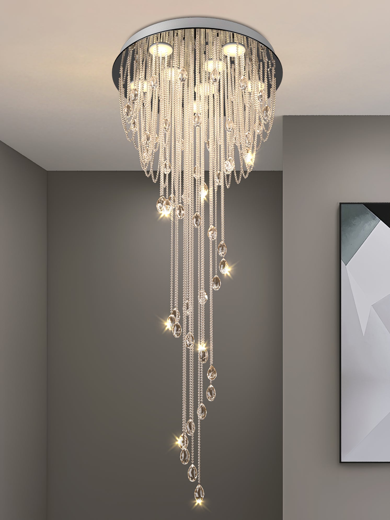 Close crystal spiral with round chrome ceiling disc and teardrop-ended strands, beside framed geometric artwork