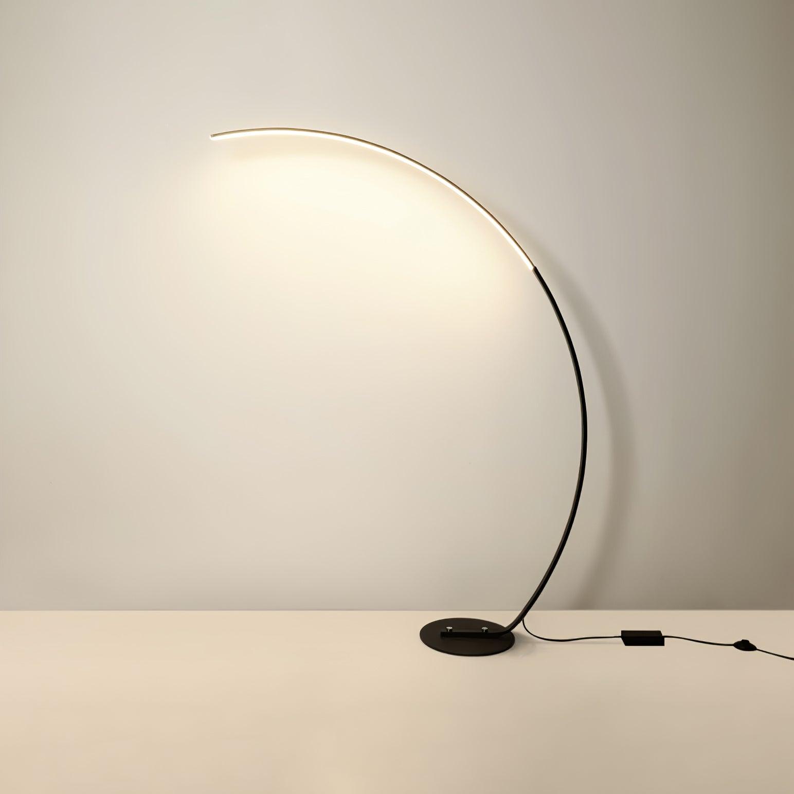 Black version of Arc floor lamp with low base, black rectangular cable box and round switch, on plain background
