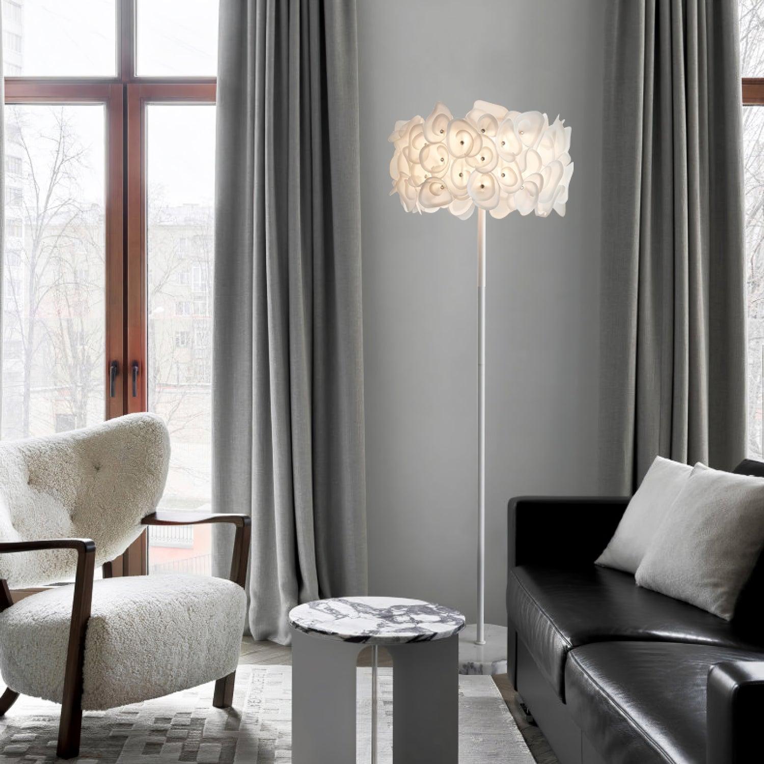 White petal lamp between cream wooden-arm chair and black sofa, gray curtains, with purple-veined table in foreground