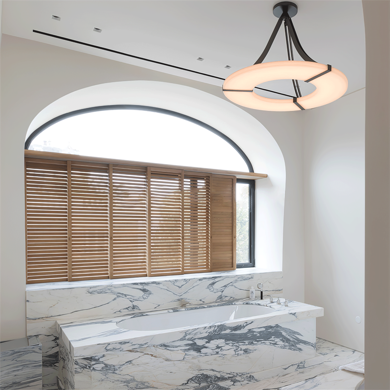 Lit halo pendant above marble-pattern bath and ledge beside arched window with wooden blinds
