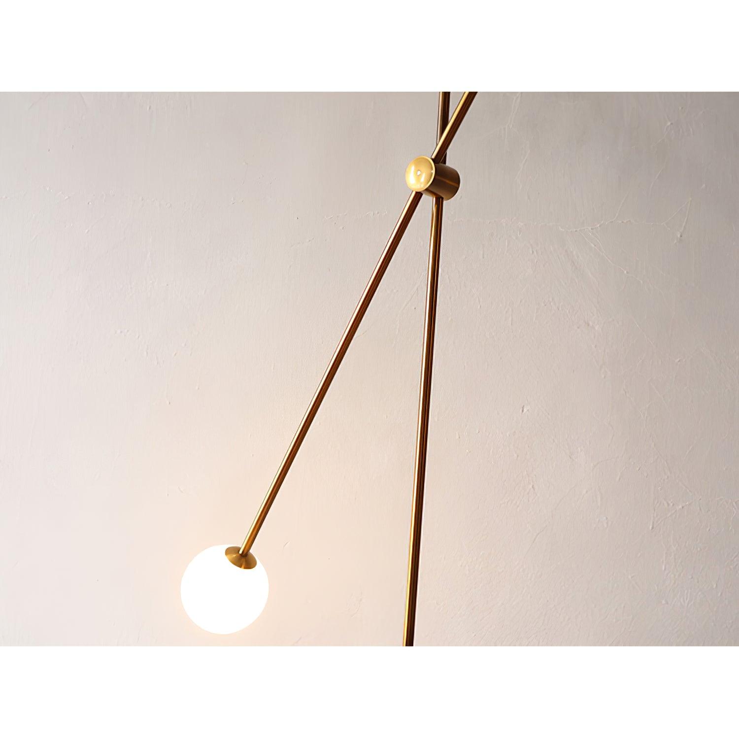 Kemi lower diagonal gold arm ending in a glowing white globe and tapered cup beside the slender upright pole