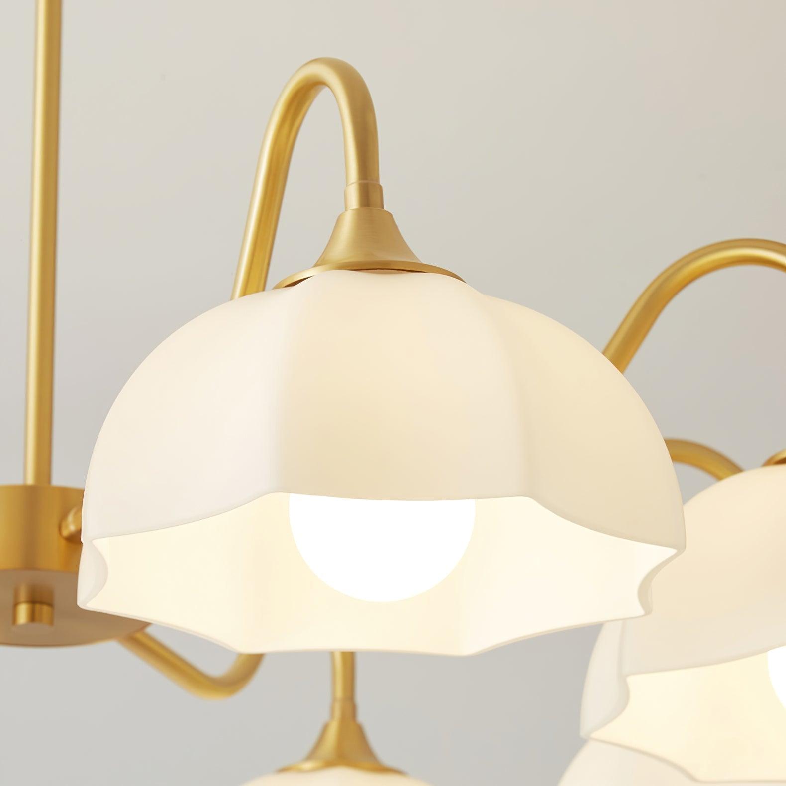 Close view of scalloped white glass shade and curved brass arm