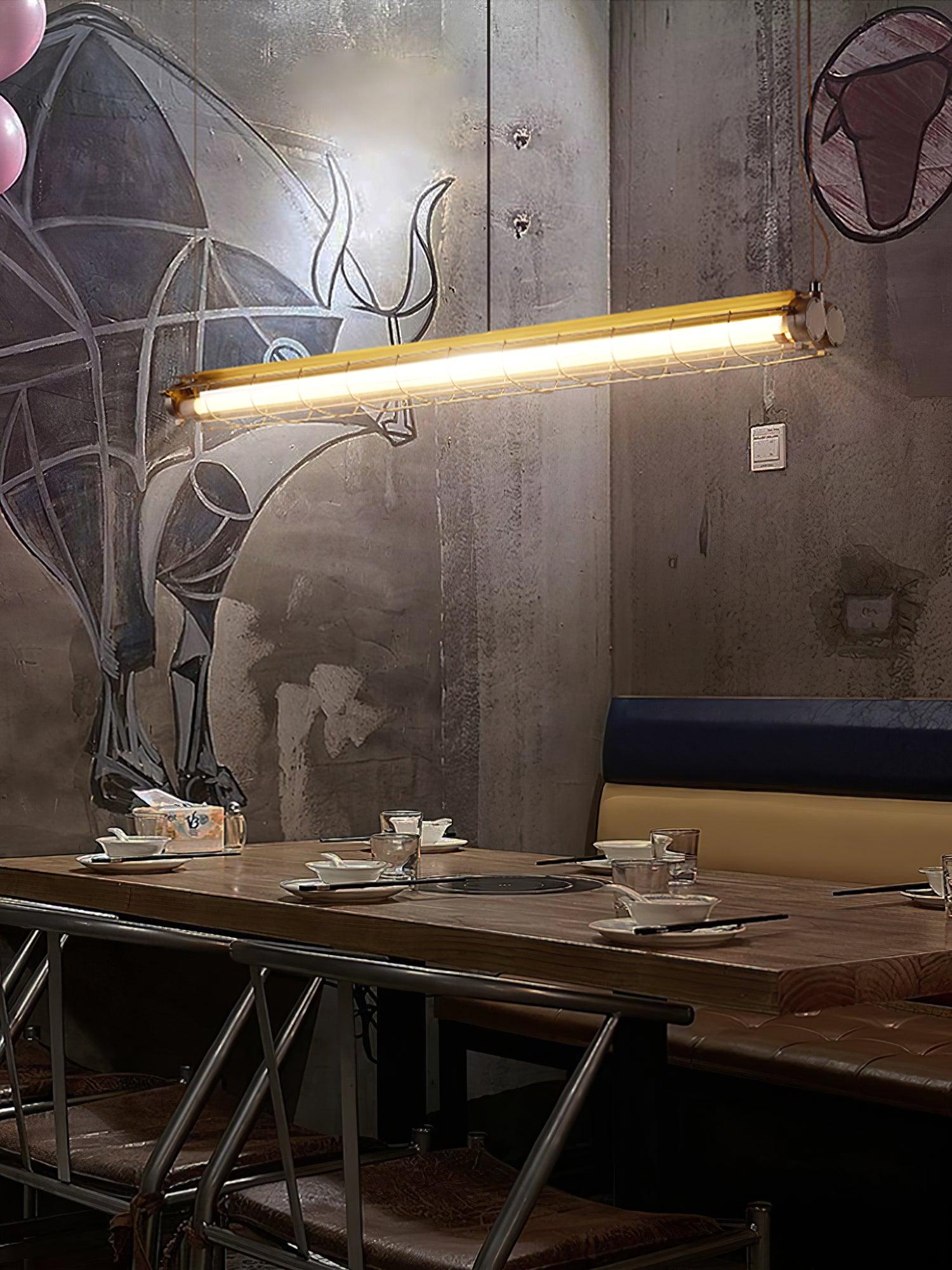 Wider view of Artisan Glass lighting above wooden tables beside a wall mural