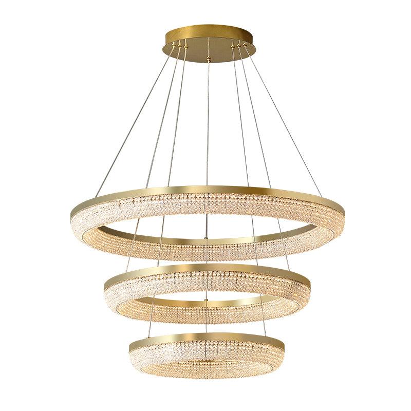 Isolated three-tier crystal ring chandelier with gold rims and round canopy against white background