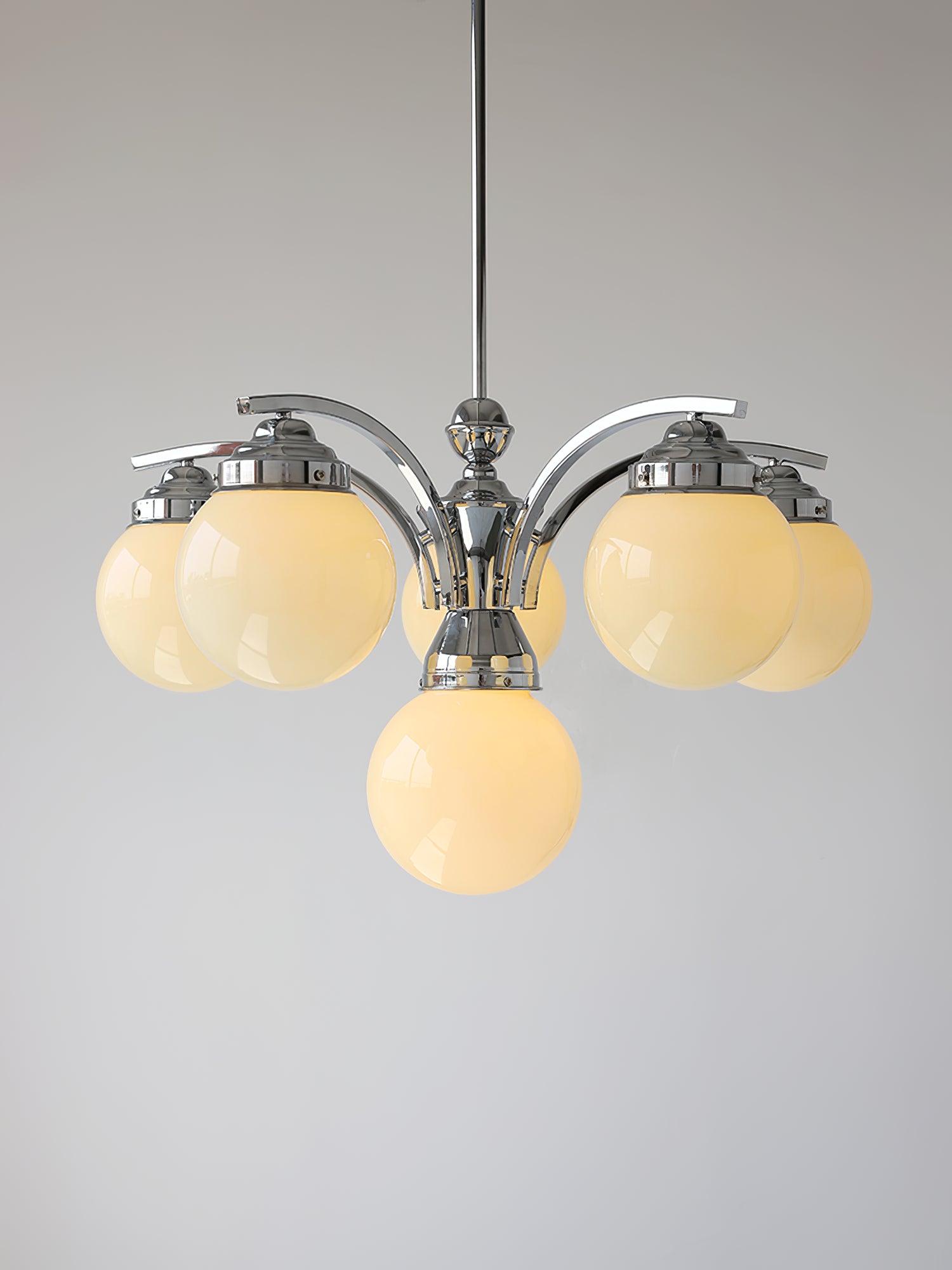 Larger downward-arm Dewdrop with warm-looking glass globes and a central lower globe against grey