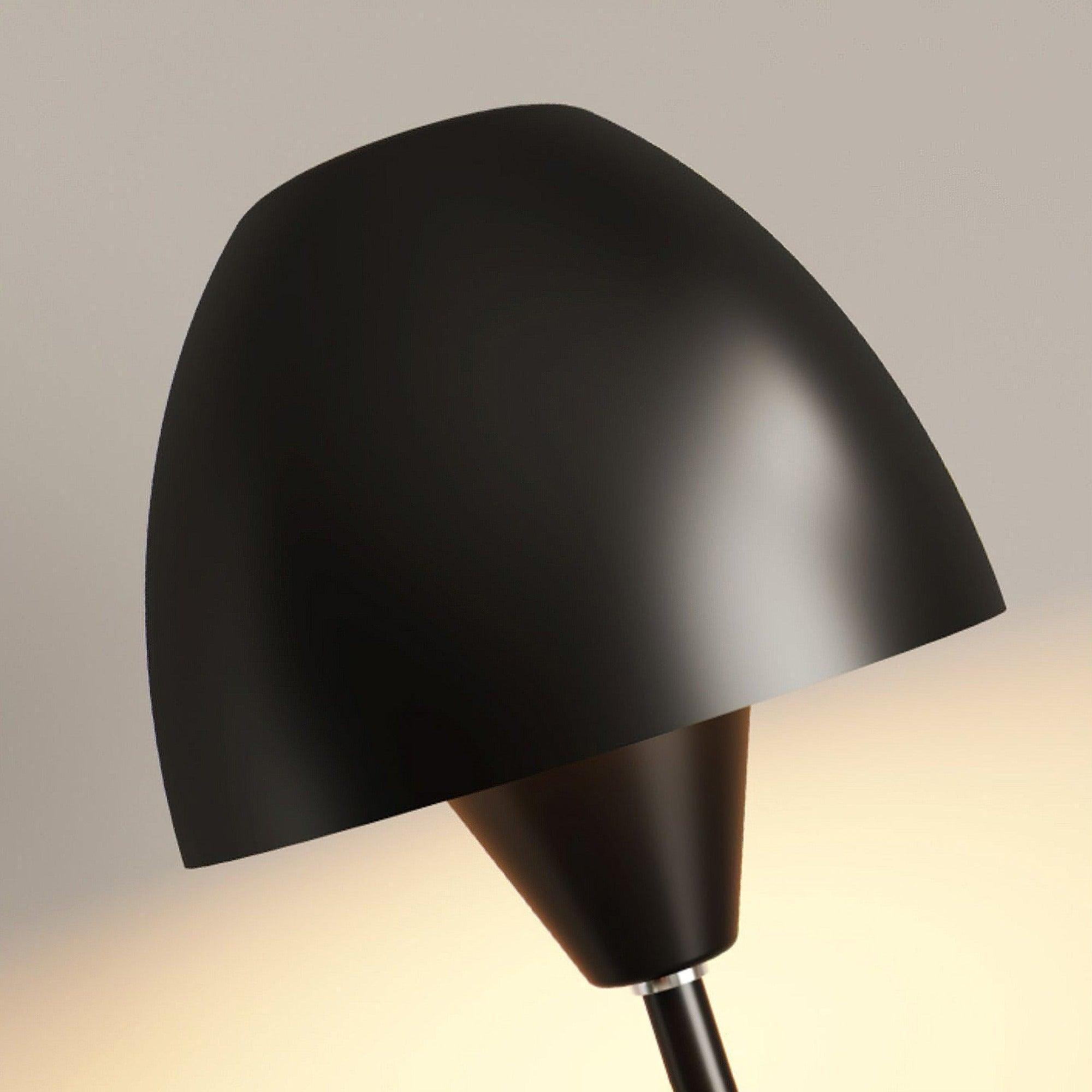 Angled close view of the black rounded shade and smaller tapered cup, with light visible behind them