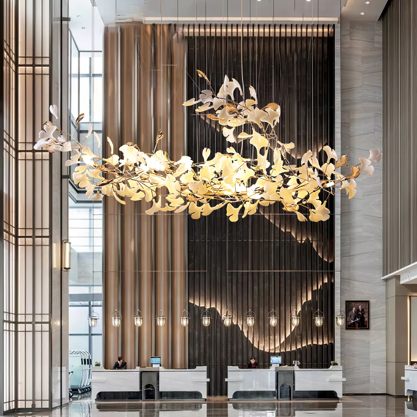 Upward-curving leaf chandelier before dark relief wall and gold-toned column above marble reception counter