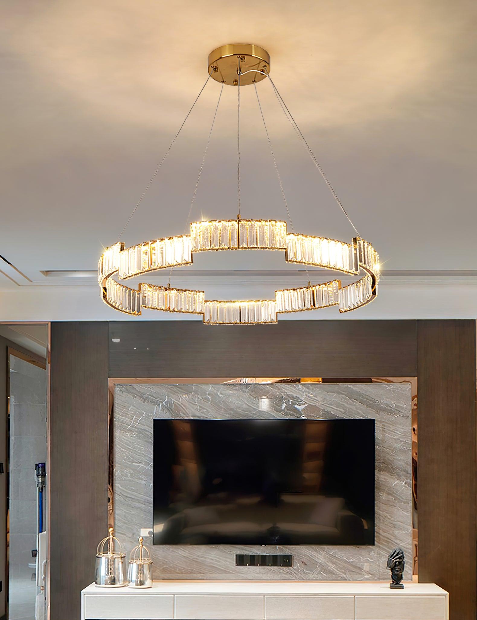 Wide view of ring chandelier above a television wall and console with glass-covered decorations and black head sculpture
