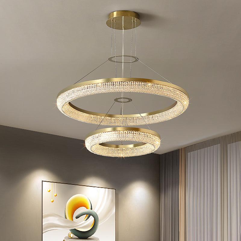 Two-tier gold crystal chandelier with larger ring above smaller ring beneath a round canopy