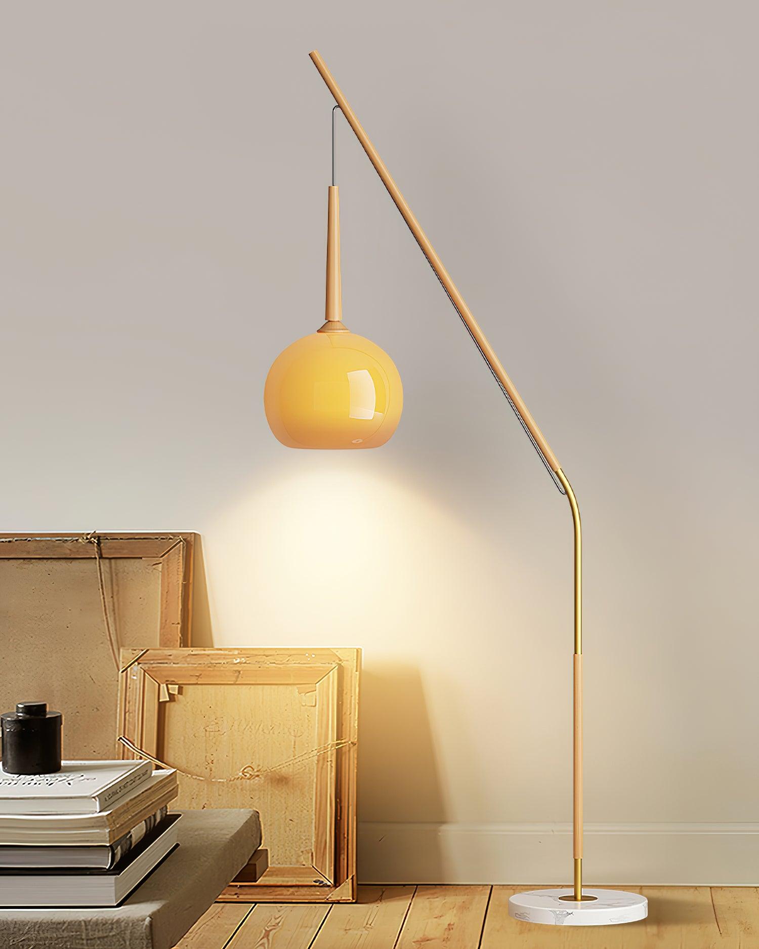 Full natural wood-colour lamp with orange shade and marble base beside picture-frame backs and books on a bench