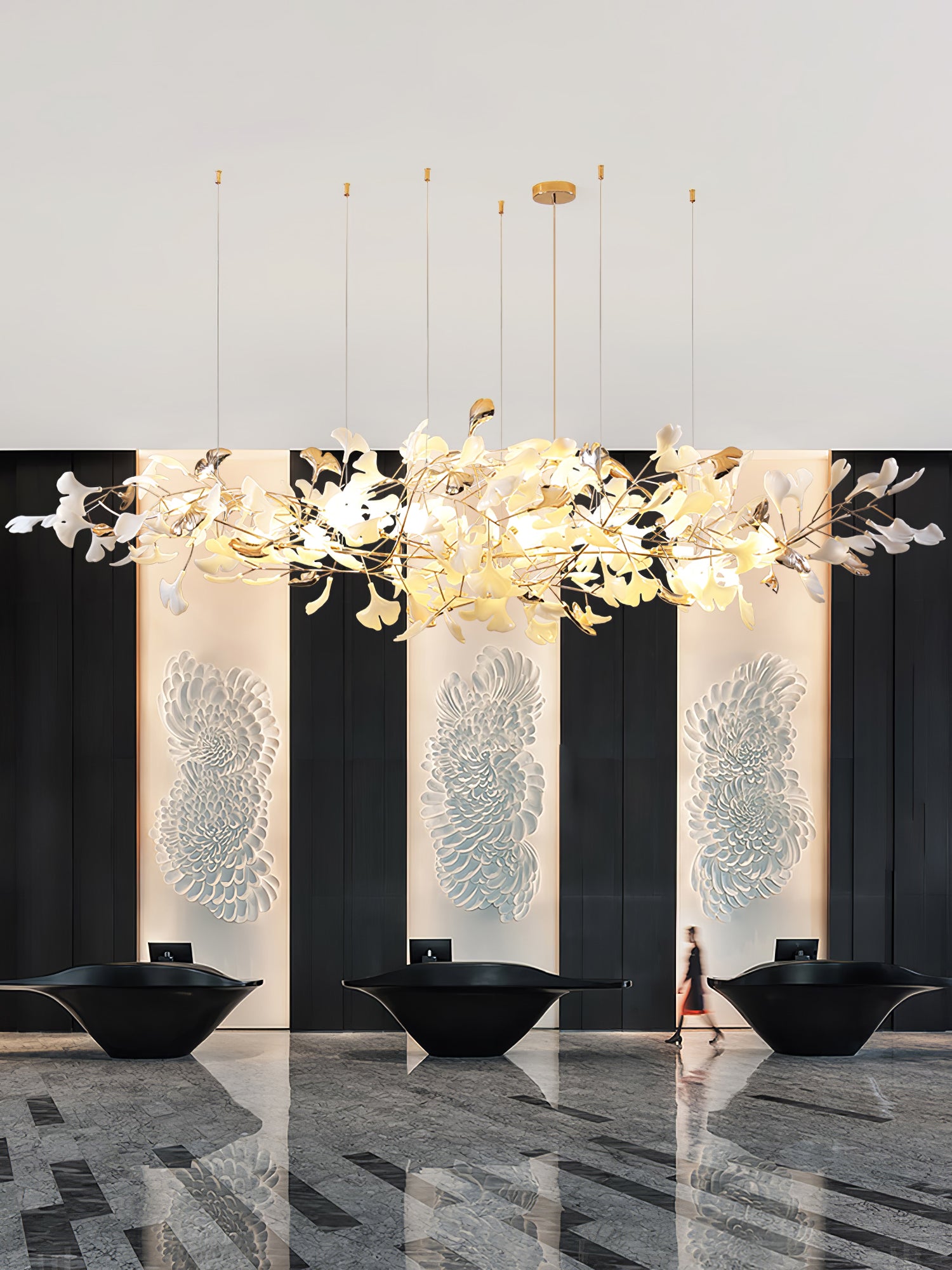 Portrait reception scene with leaf cloud above three black desks, white petal wall reliefs and patterned floor