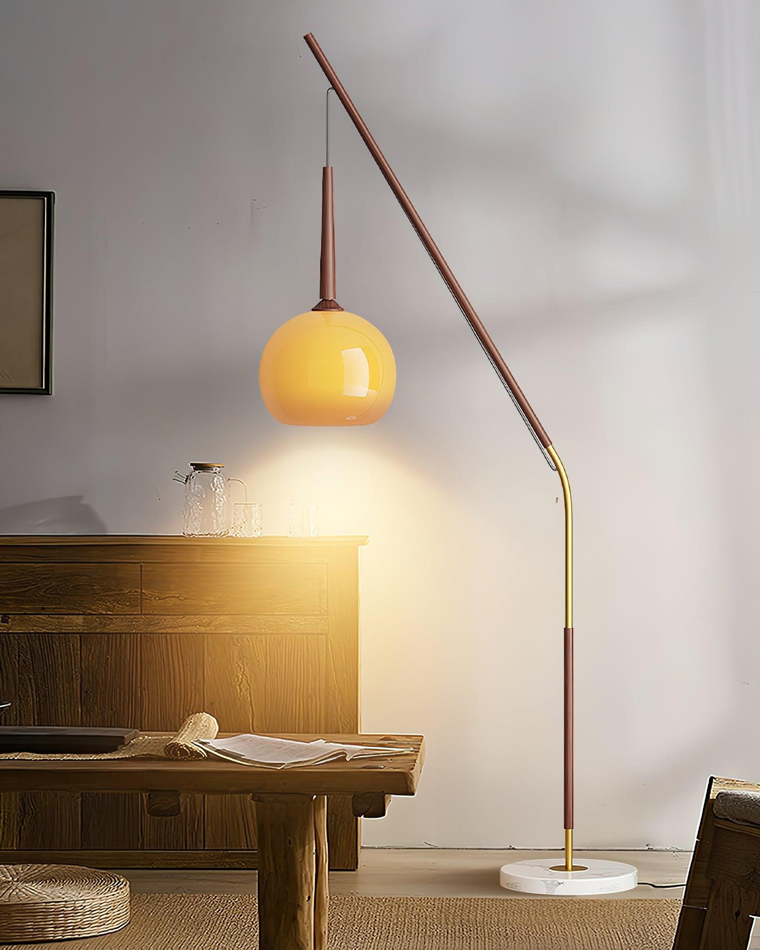 Dark wood-colour lamp with orange hanging shade above a console holding a glass jug and tumblers, with marble base below