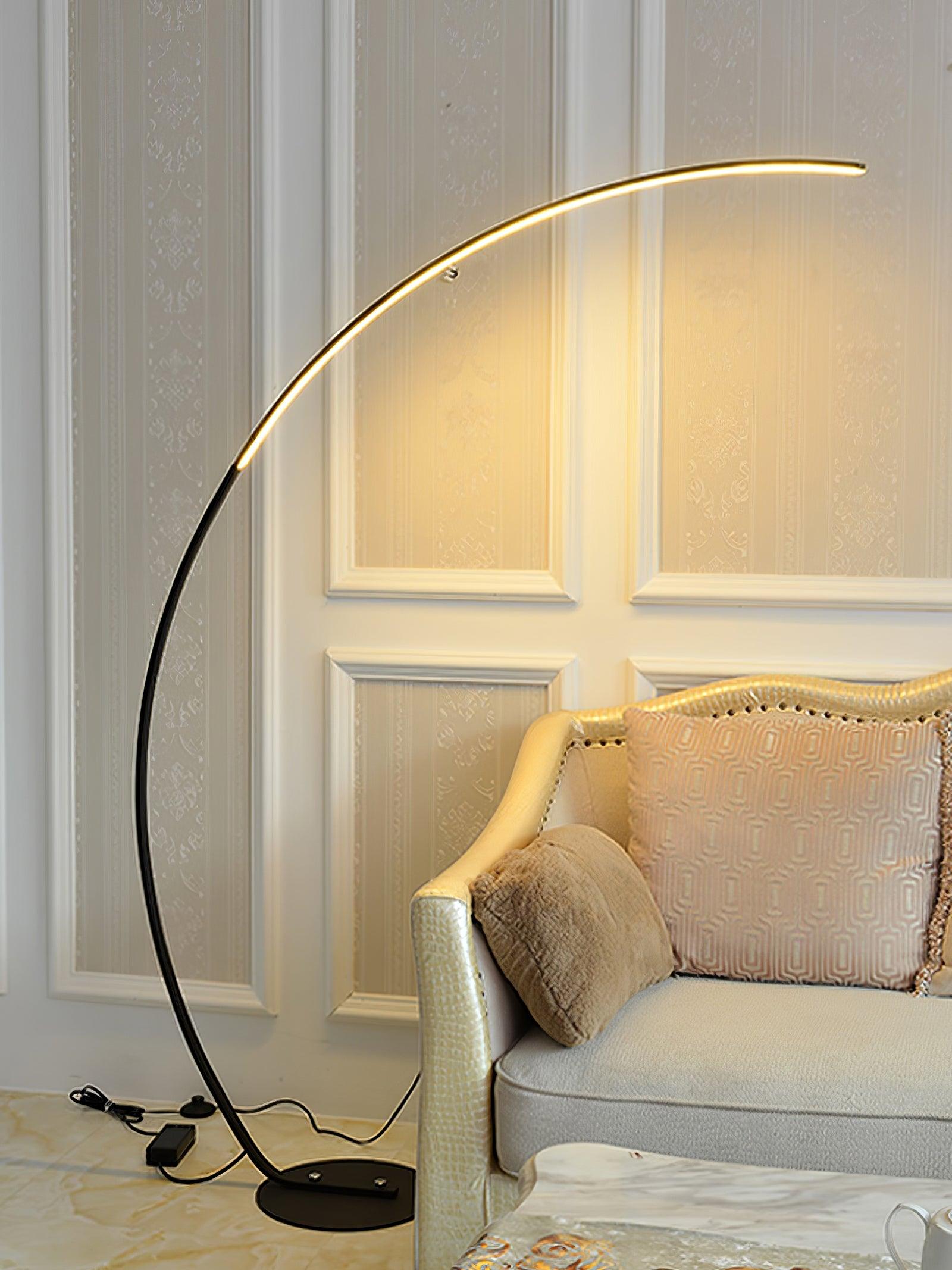 Black Arc floor lamp beside ornate cream sofa, with cable, round switch and rectangular power box visible on the floor