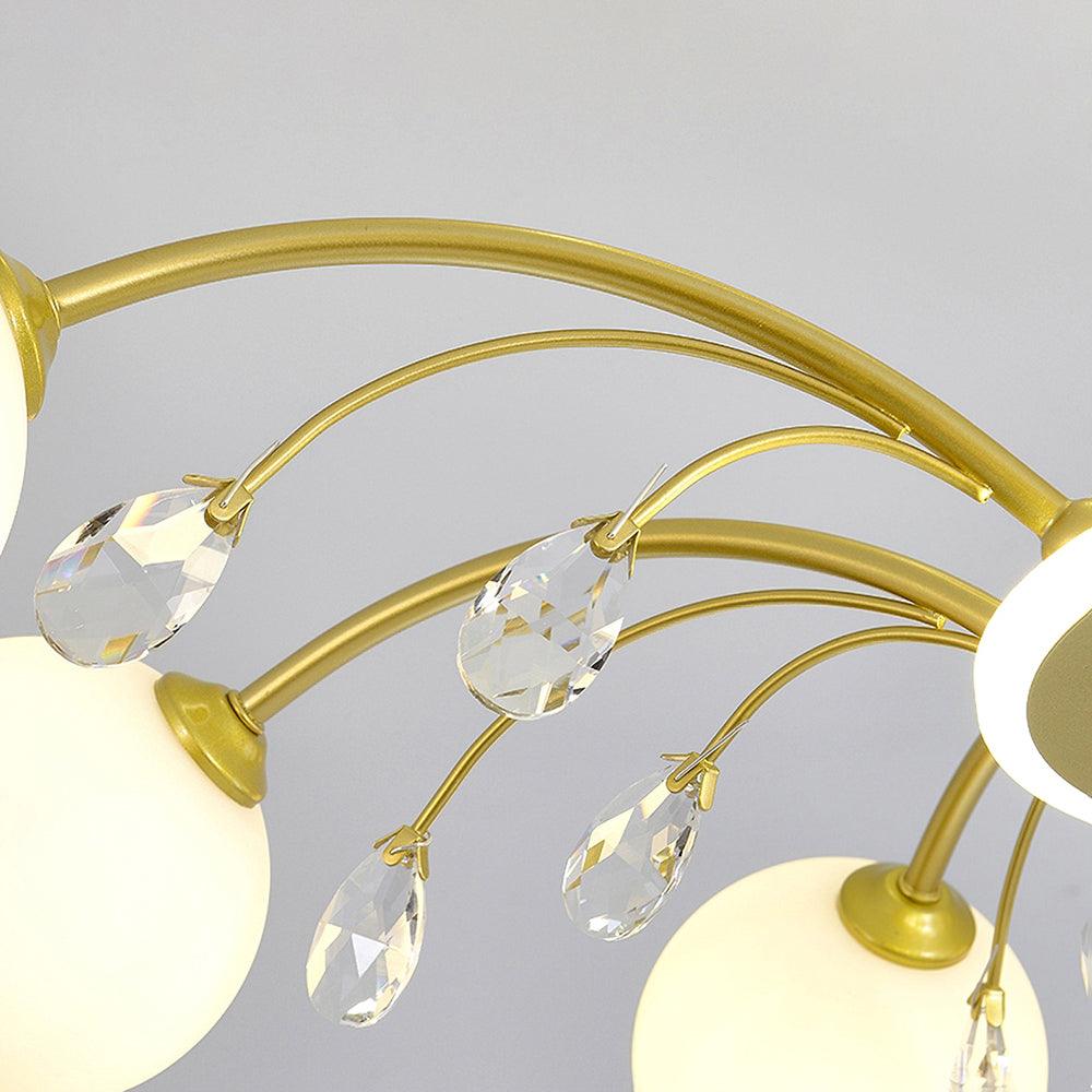 Close-up of Gold curved arms, separate clear faceted teardrops on slender stems and white spherical shades