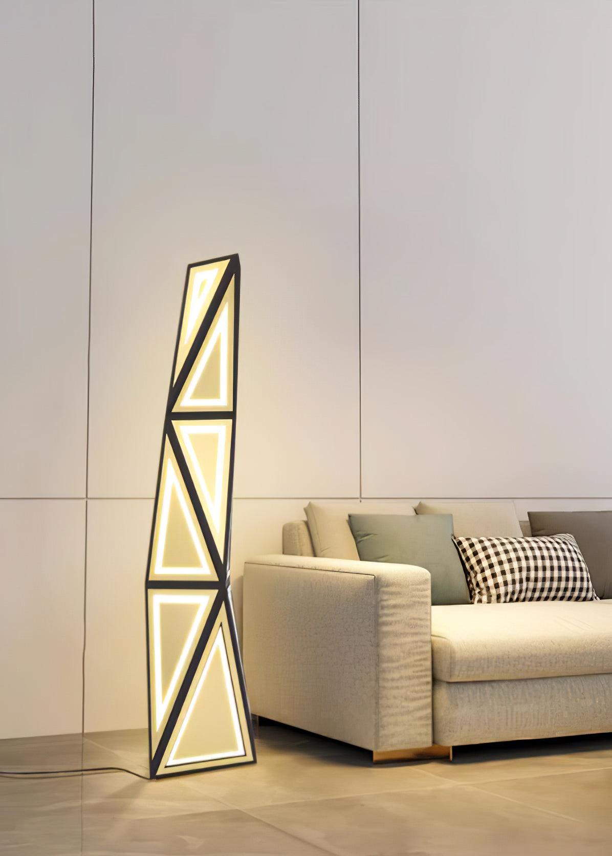 Full view of the triangular-light floor lamp beside a beige sofa and checked cushion