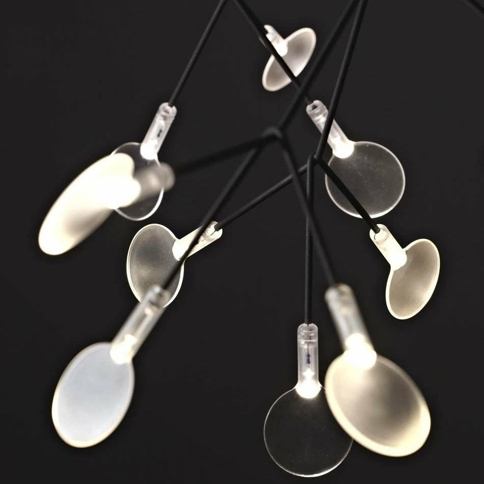 Close-up of black branches, rounded translucent acrylic petals and small illuminated cylindrical joints against black